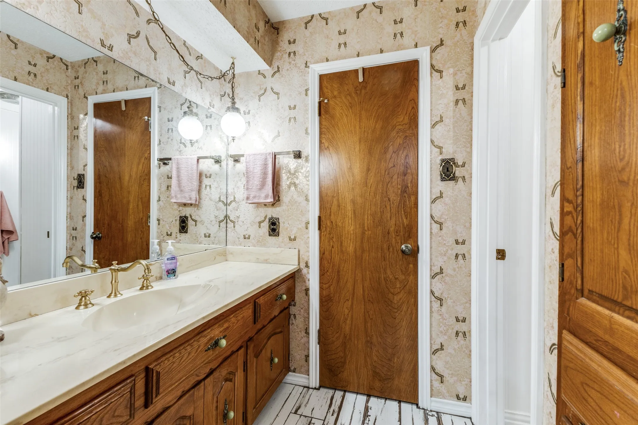Bathroom with vanity and wallpapered walls