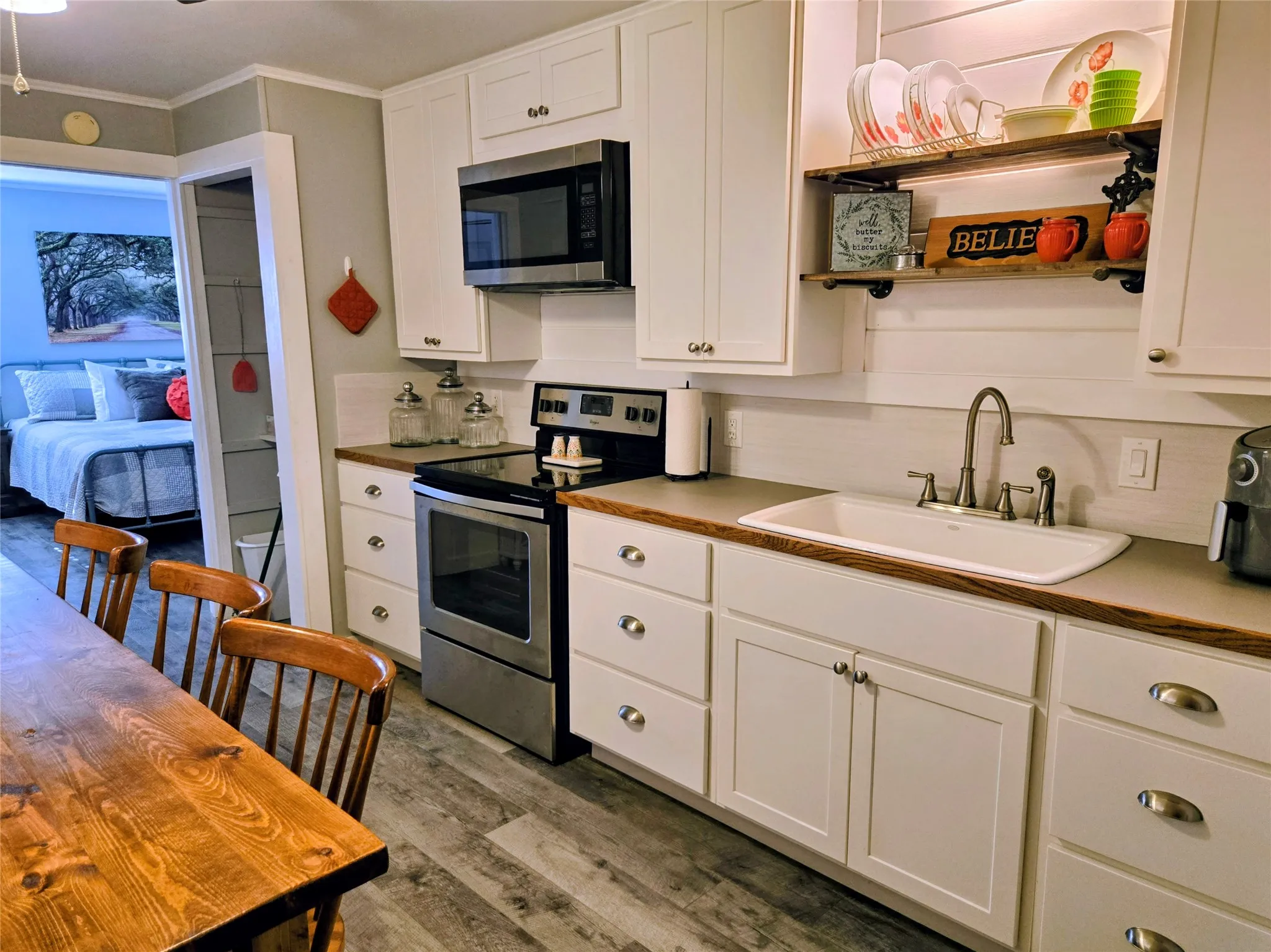 Kitchen featuring appliances with stainless steel finishes, white cabinetry, ornamental molding, dark wood finished floors, and open shelves