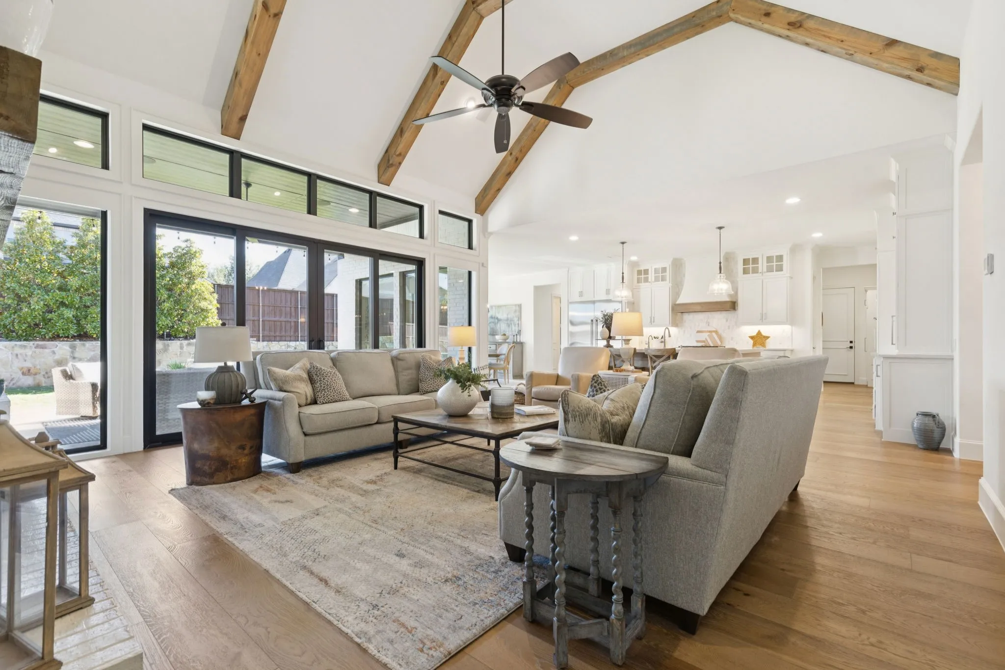 Living area with high vaulted ceiling, beamed ceiling, plenty of natural light, light wood-style flooring, and ceiling fan