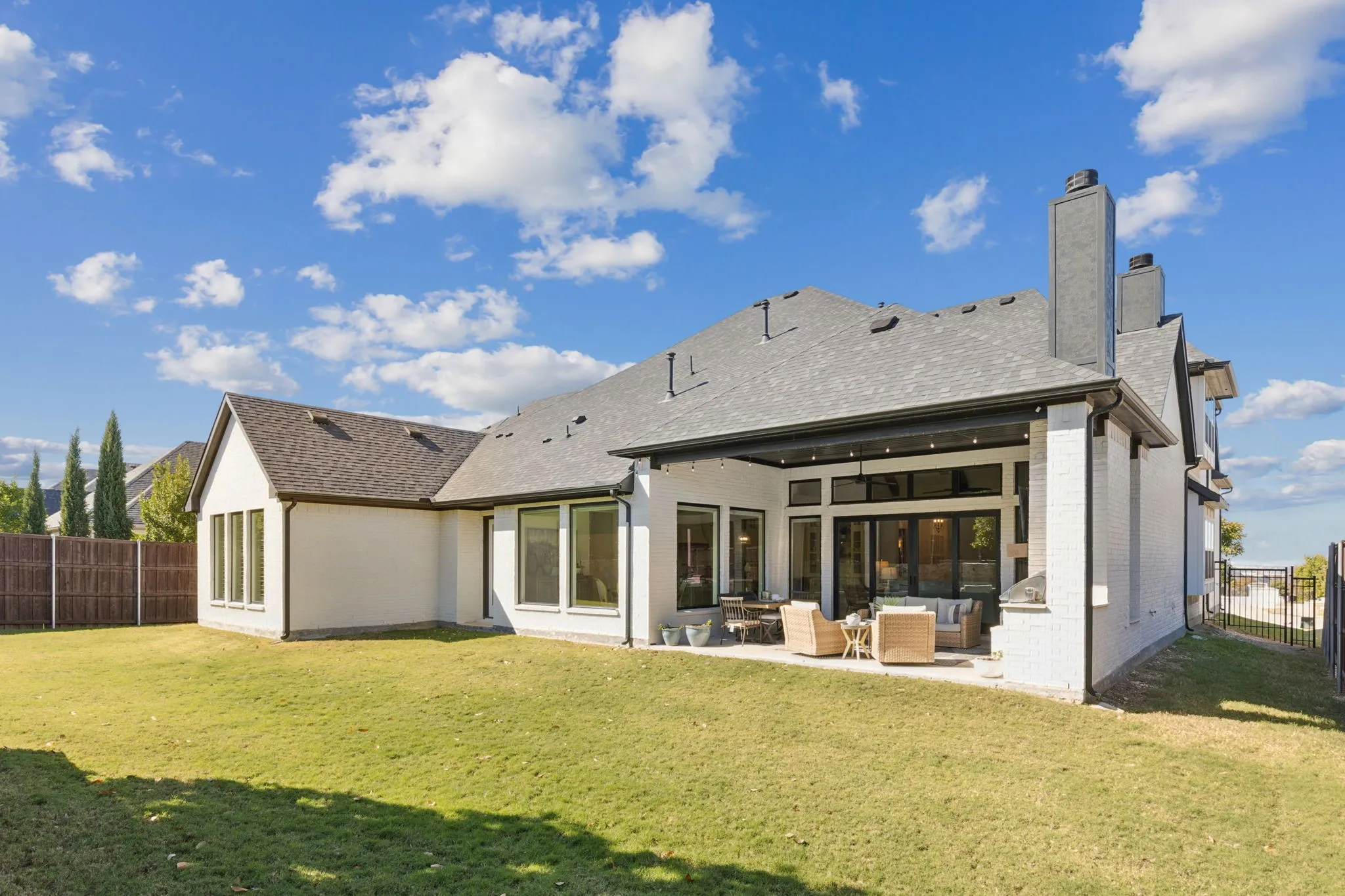 Rear view of property featuring a fenced backyard, an outdoor living space, brick siding, a patio, and a chimney