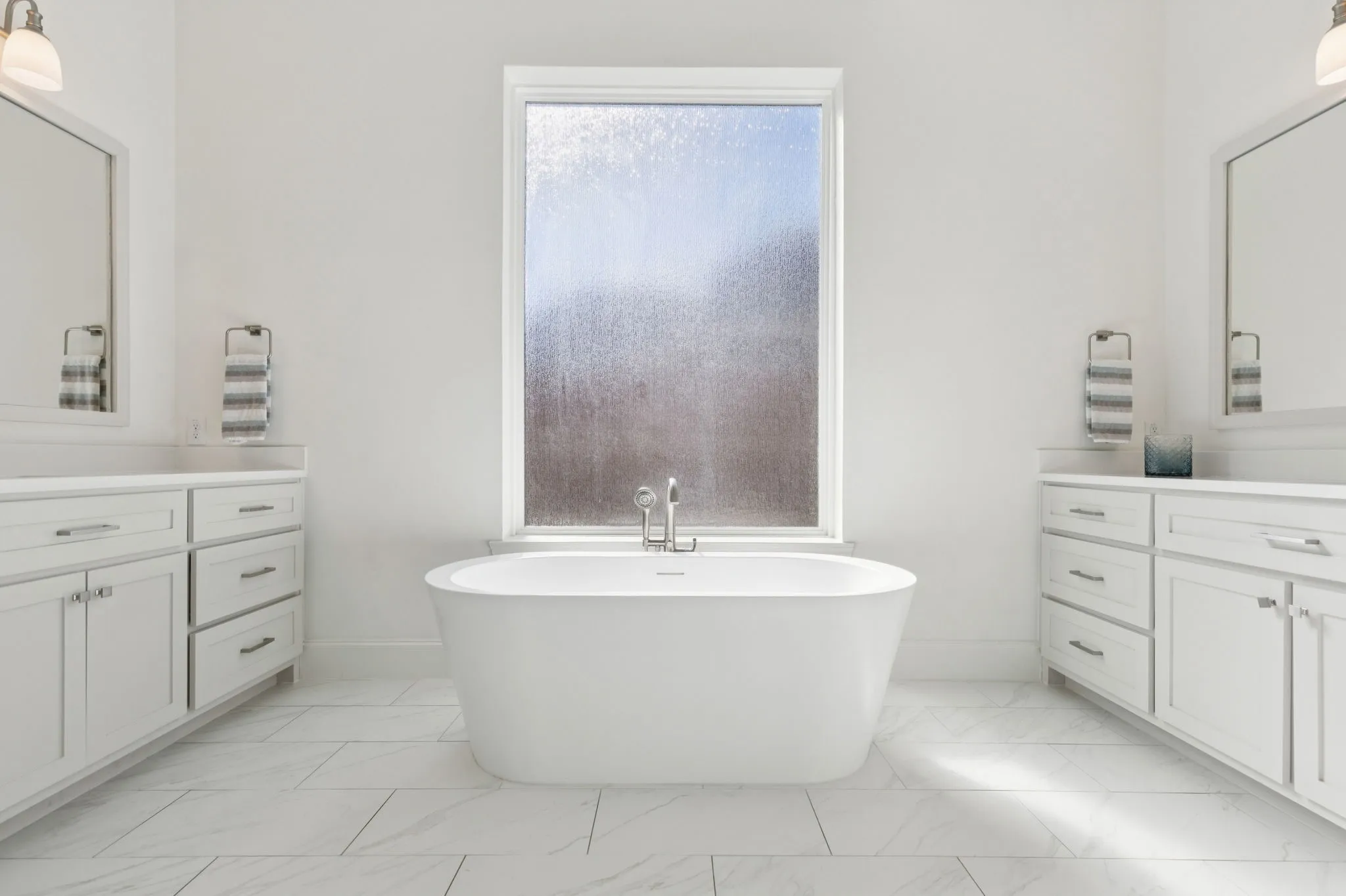 Full bathroom featuring a freestanding bath, vanity, and light marble finish flooring