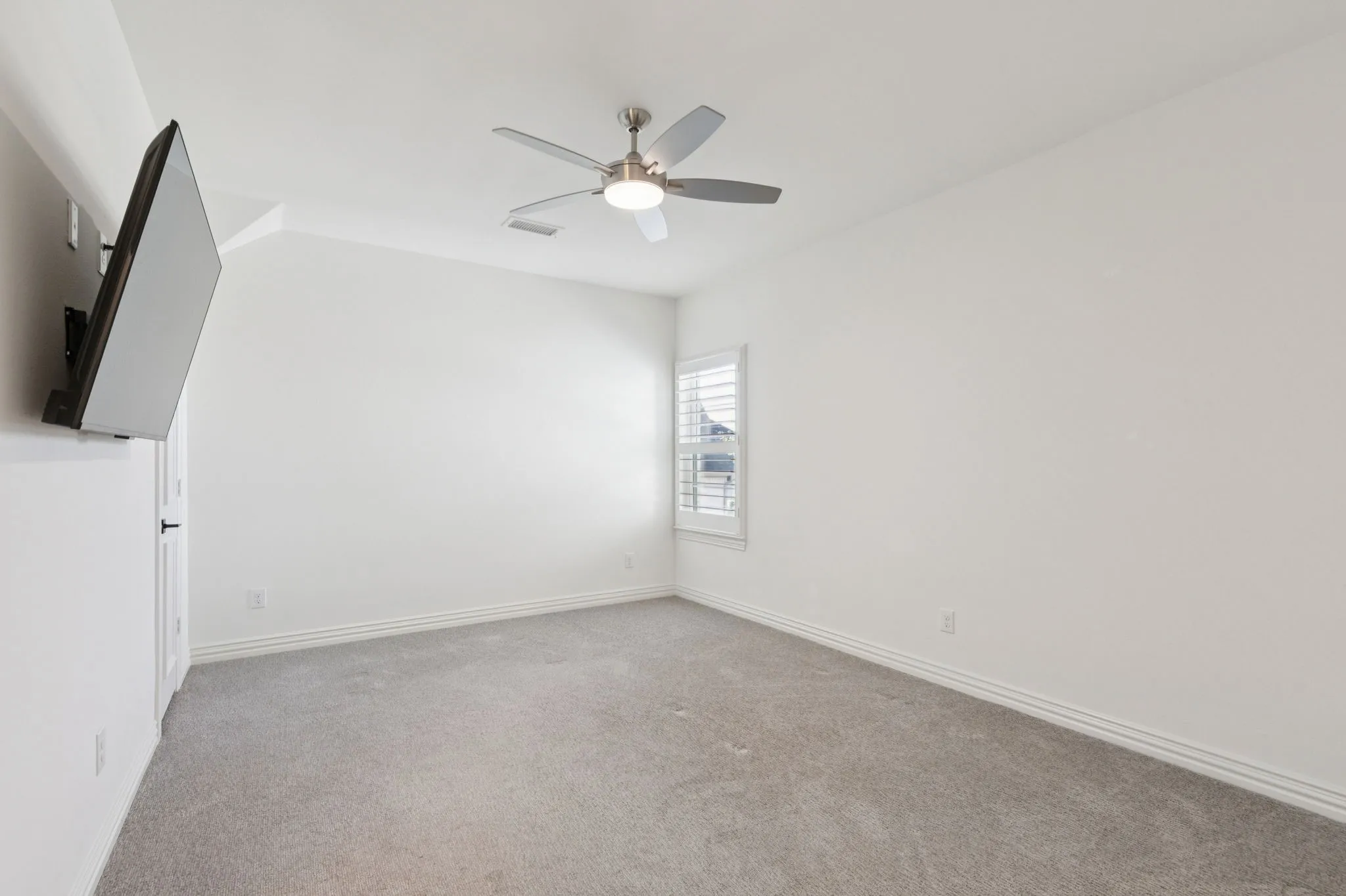 Empty room featuring light colored carpet and a ceiling fan
