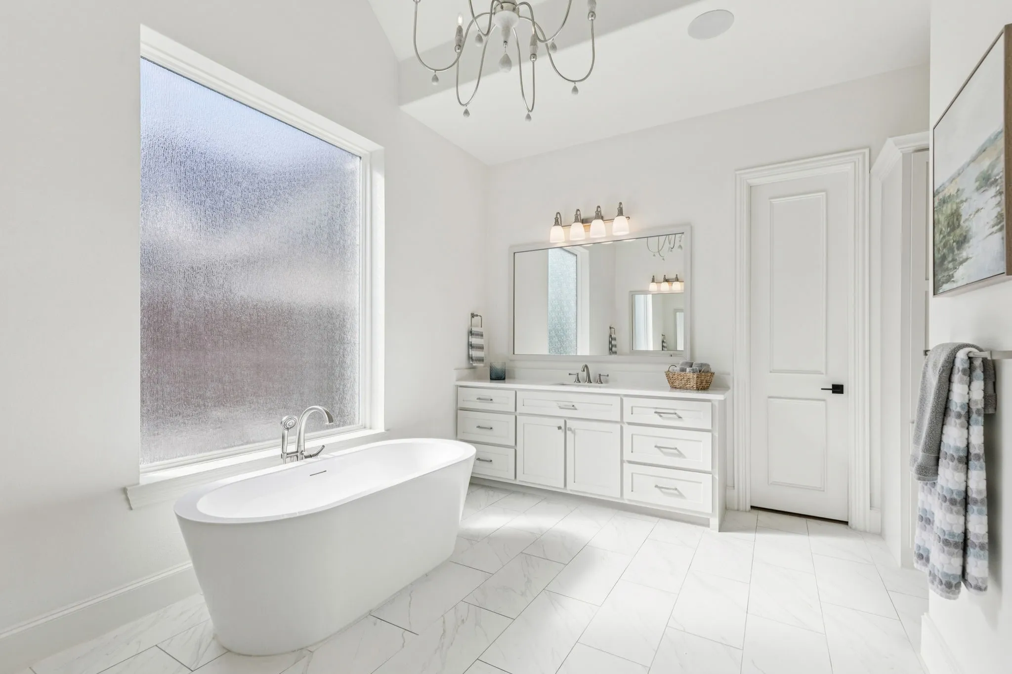 Full bath with vanity, a soaking tub, a chandelier, and light marble finish flooring