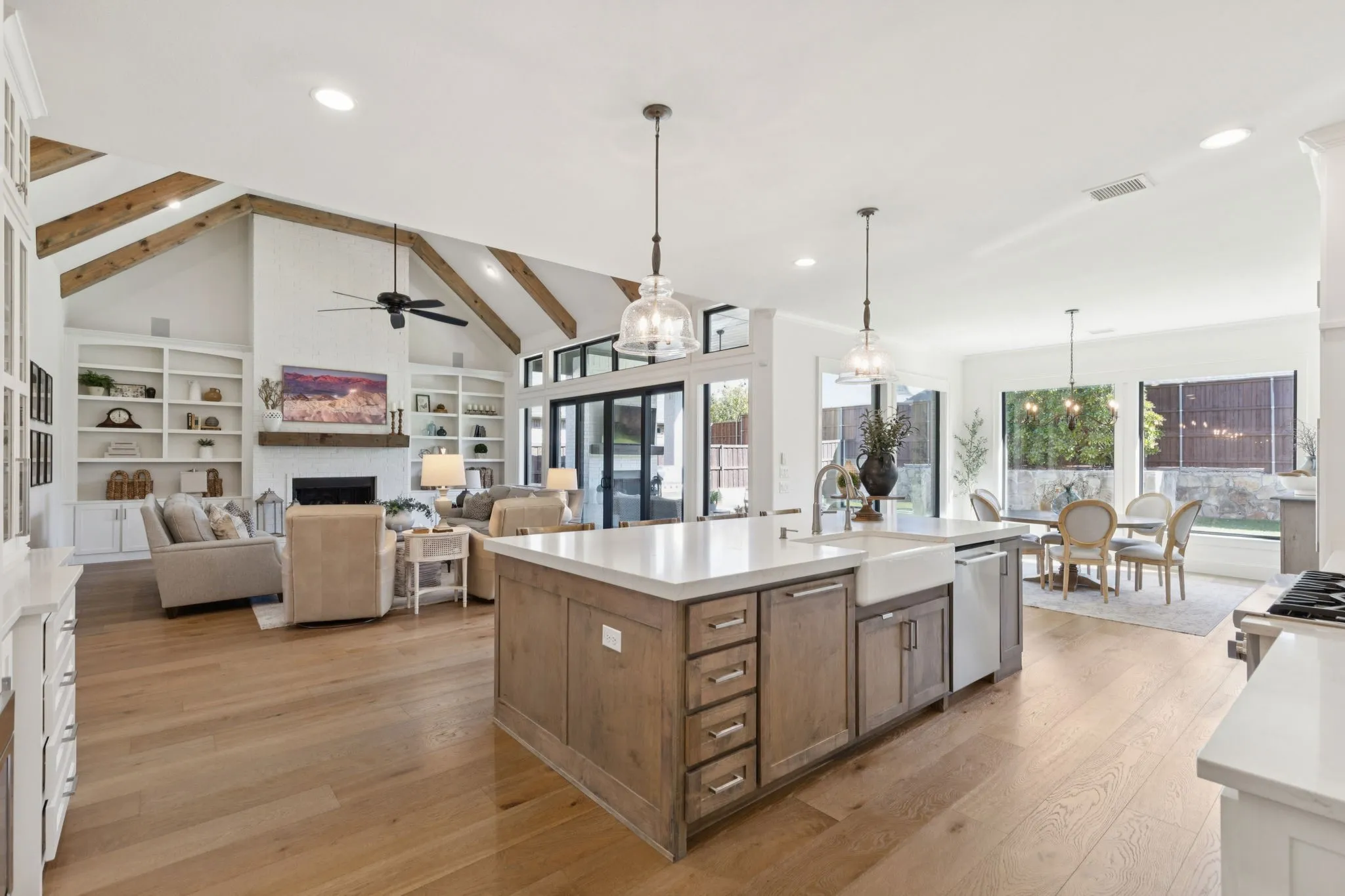 Kitchen featuring a fireplace, a chandelier, pendant lighting, light wood-style floors, and beam ceiling