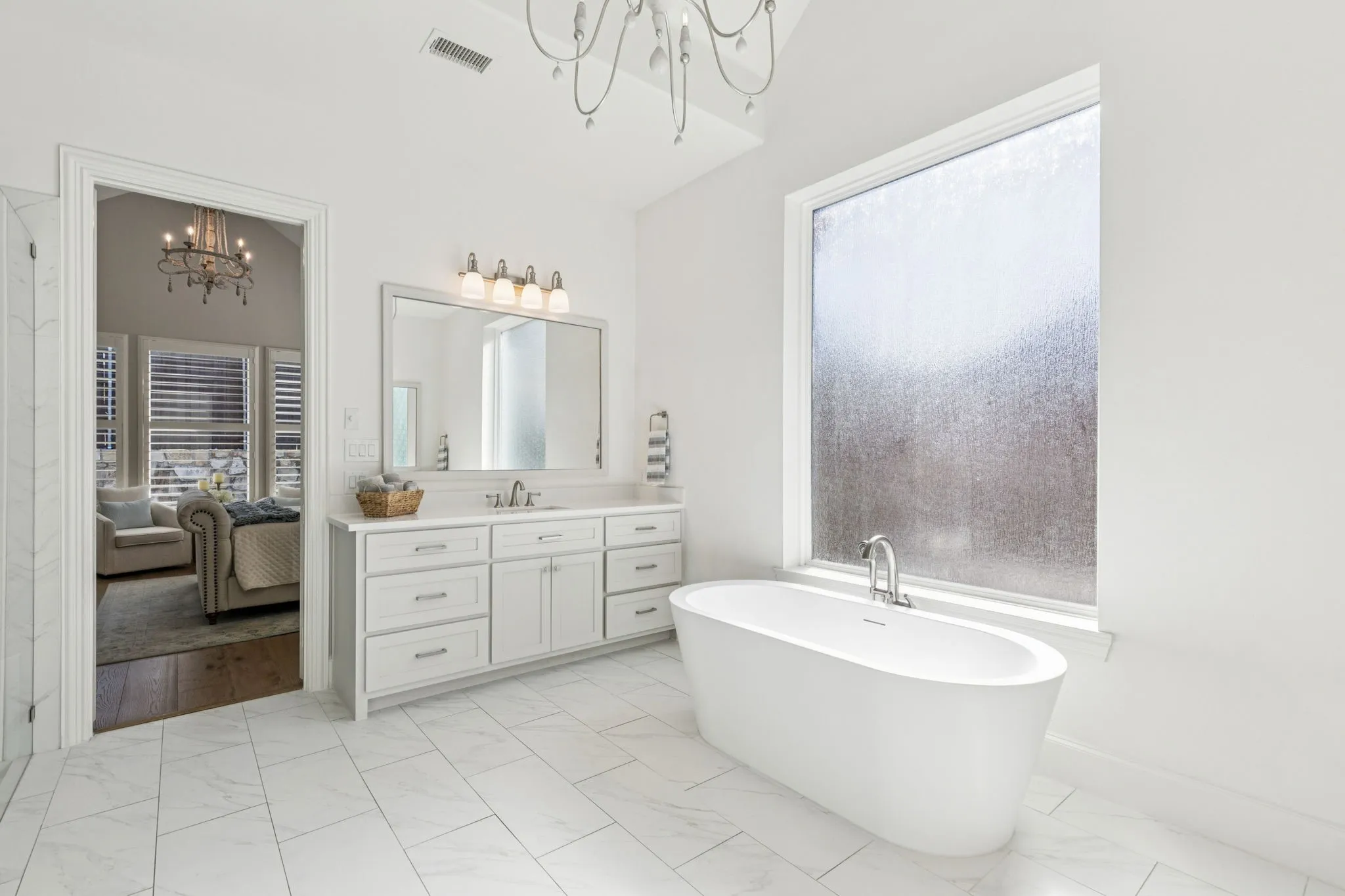 Ensuite bathroom with a chandelier, vanity, a soaking tub, and light marble finish floors