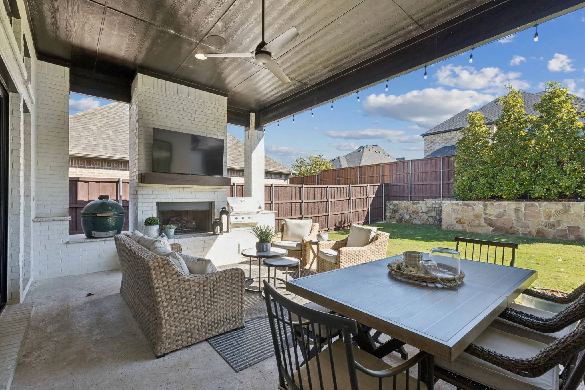 Fenced backyard with ceiling fan, a patio, outdoor dining area, an outdoor living space with a fireplace, and grilling area