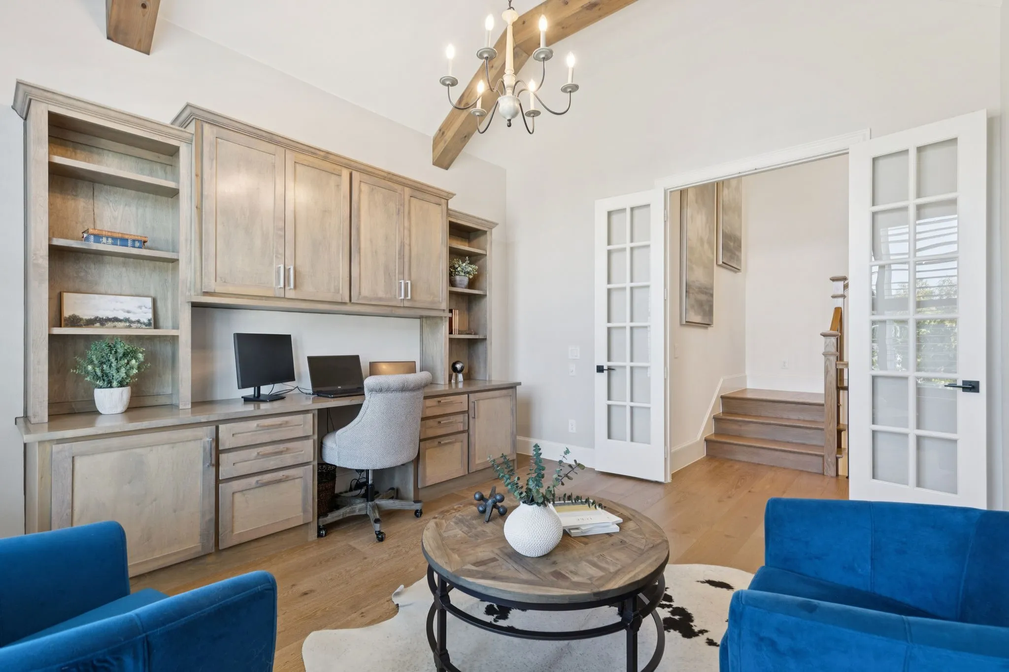 Office featuring built in study area, beamed ceiling, light wood-style flooring, french doors, and a chandelier