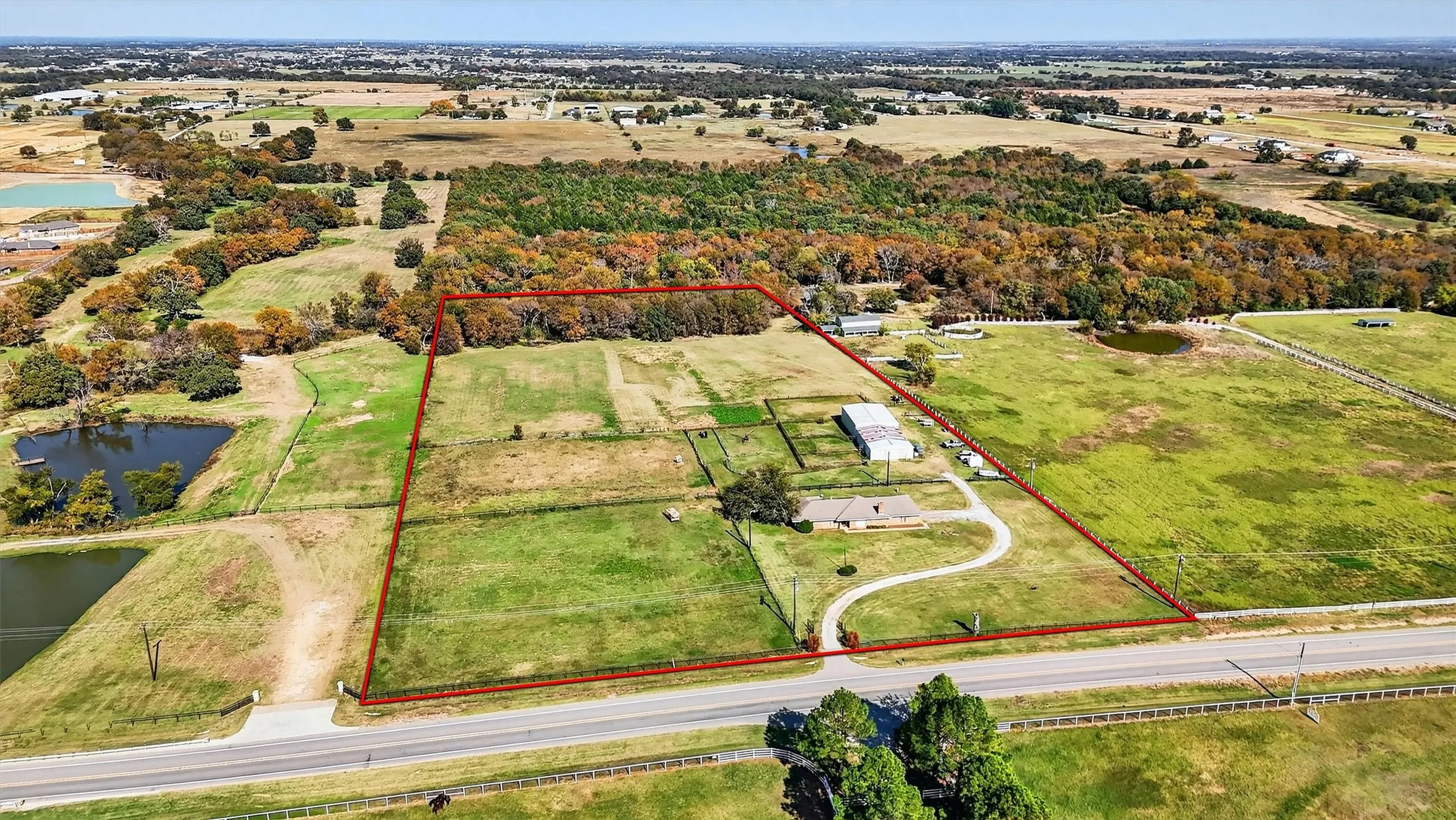 Aerial view of sparsely populated area featuring a nearby body of water and property parcel outlined