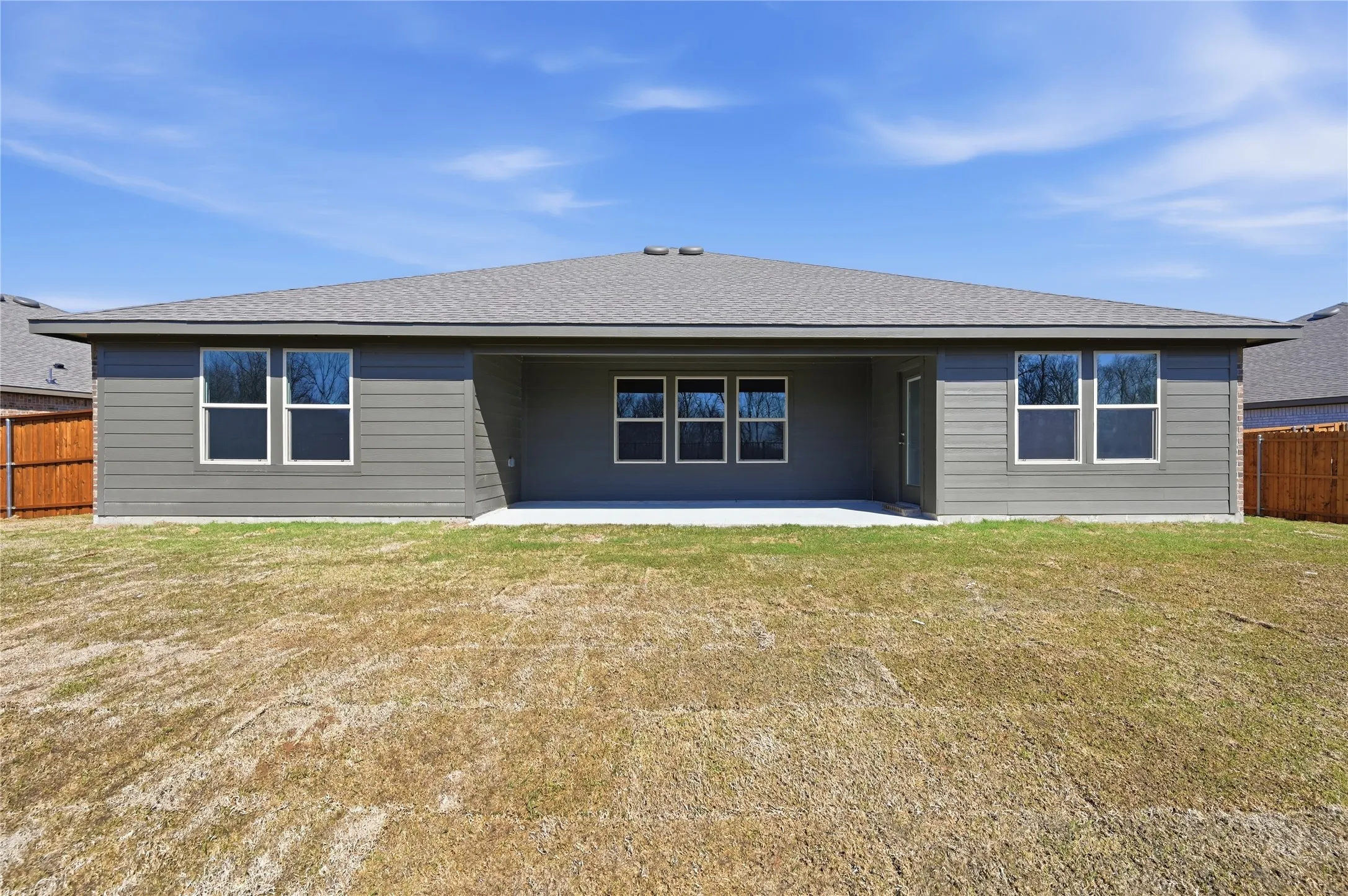 Rear exterior featuring gray horizontal siding, a covered patio, and a shingle roof
