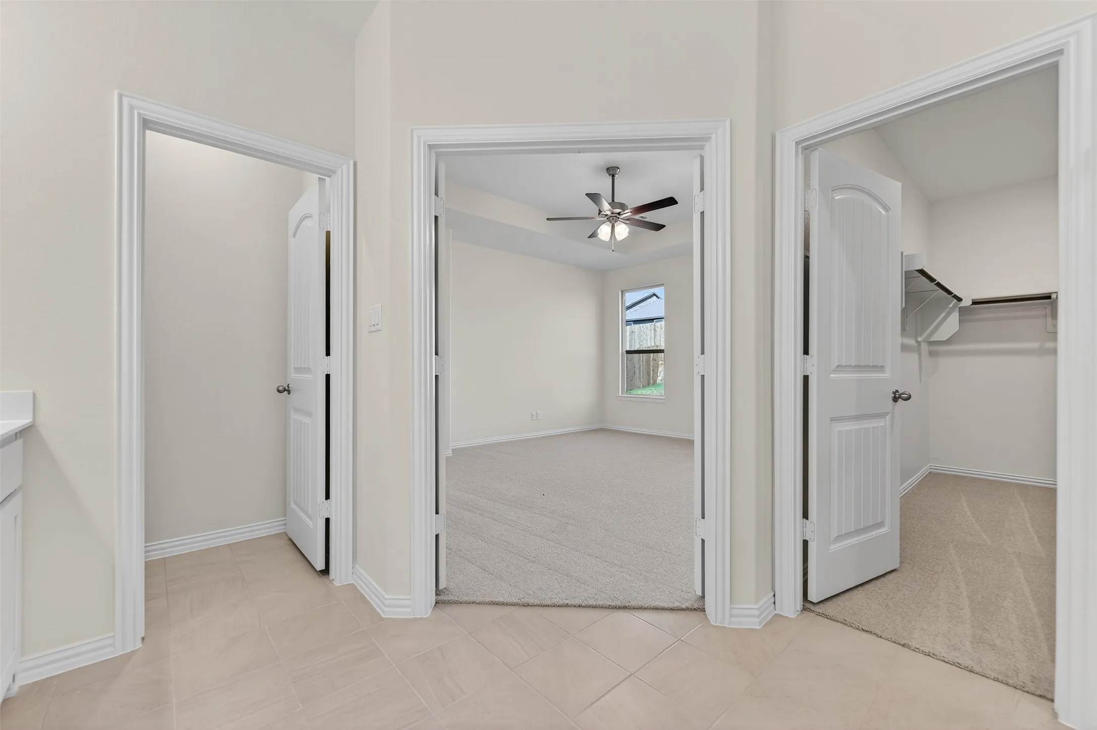 Unfurnished bedroom featuring a spacious closet, light carpet, light tile patterned flooring, and ceiling fan