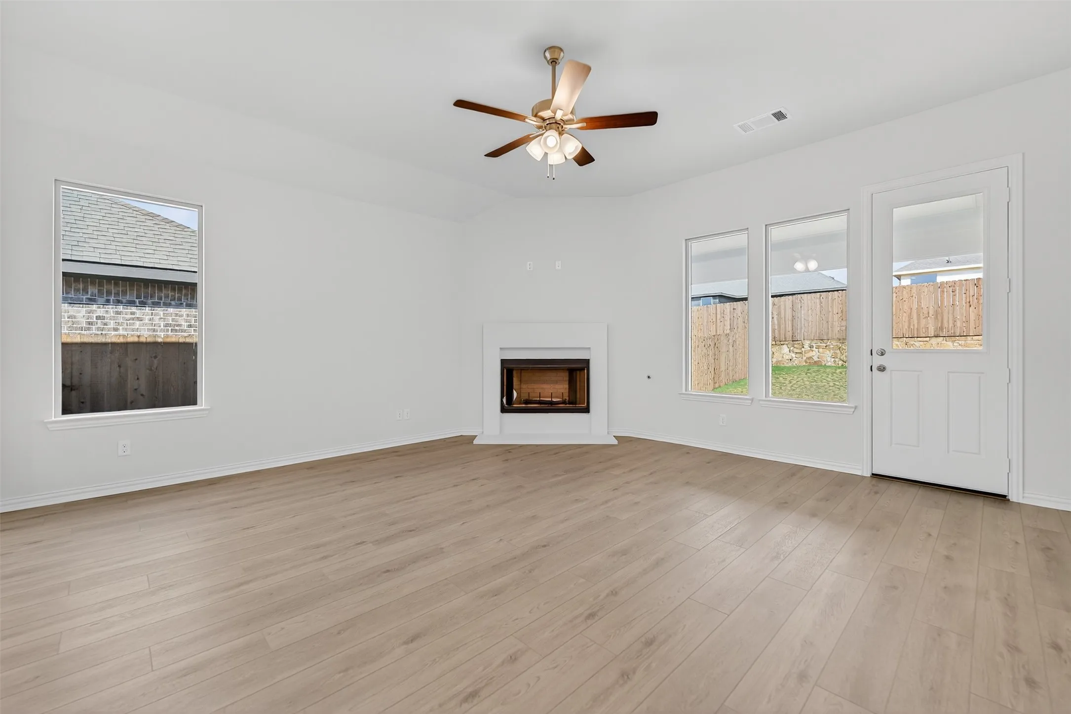 Unfurnished living room featuring a fireplace, light wood finished floors, and ceiling fan