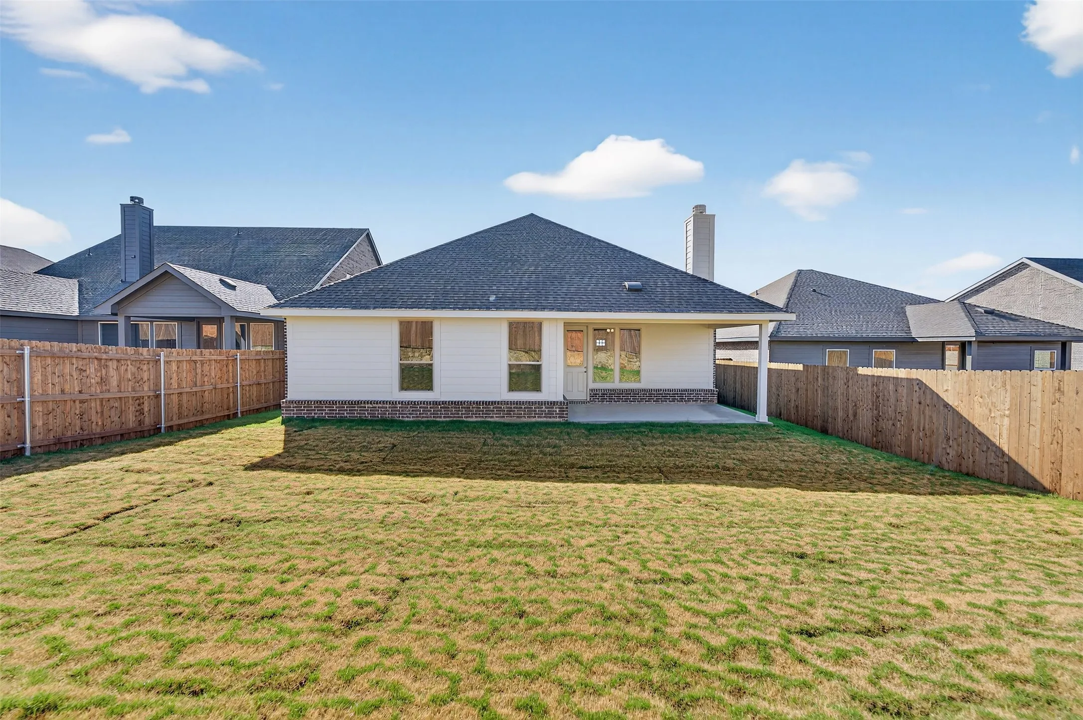 Rear view of house featuring a patio area, a fenced backyard, a shingled roof, and a chimney