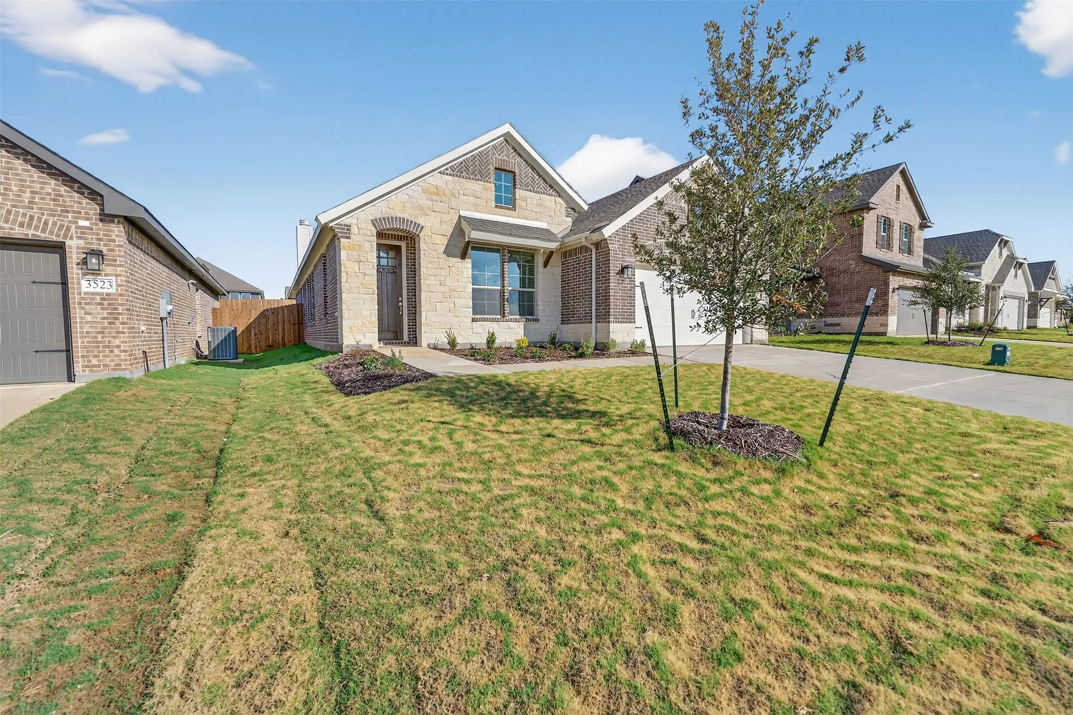 View of front facade featuring stone siding, brick siding, and concrete driveway