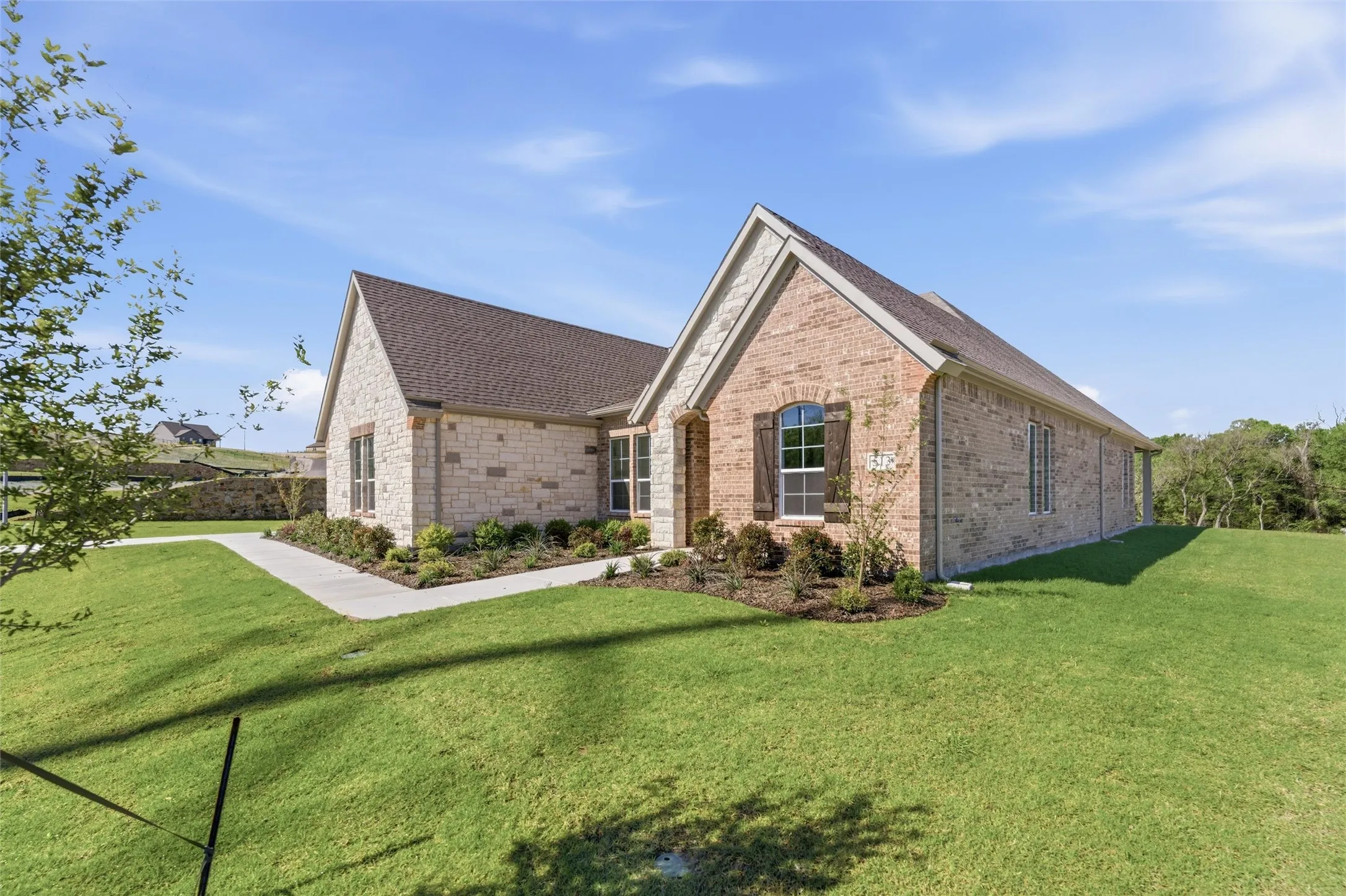 View of front of property with a front lawn, brick siding, and roof with shingles