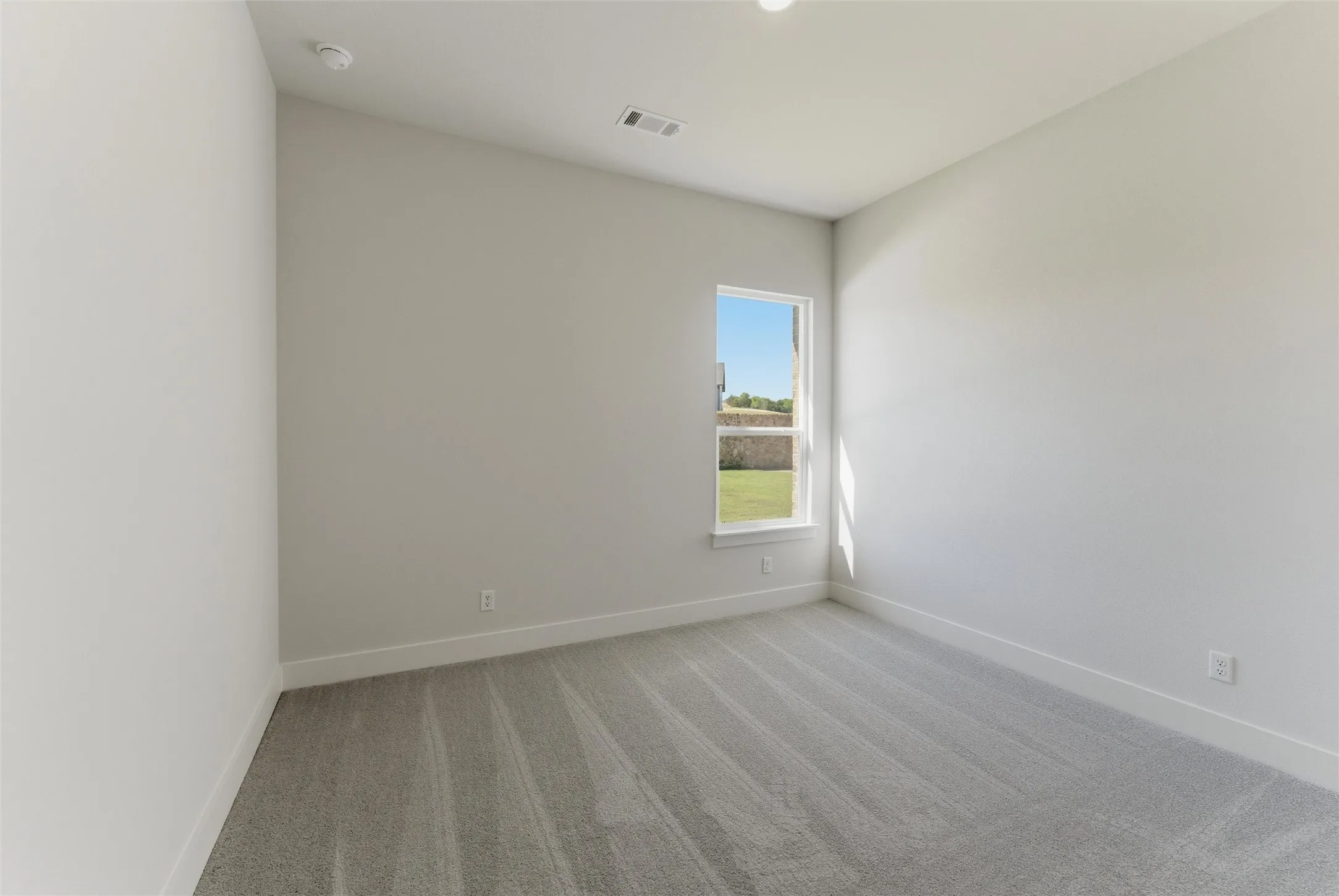 Spare room featuring light carpet and baseboards