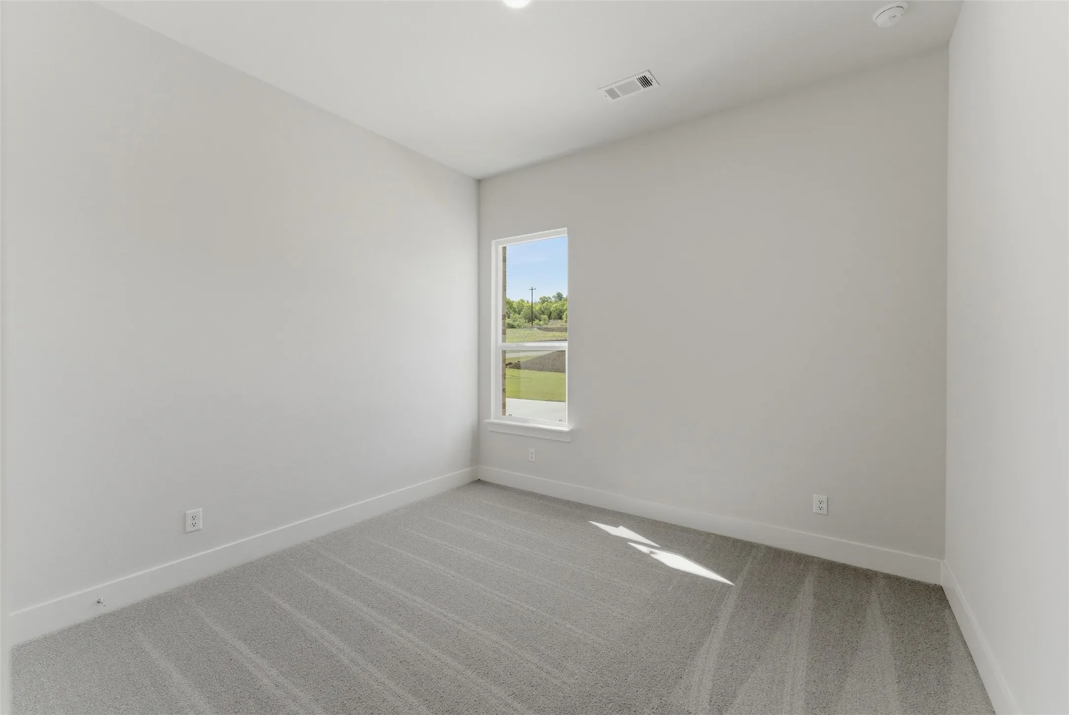 Unfurnished room featuring light carpet and baseboards
