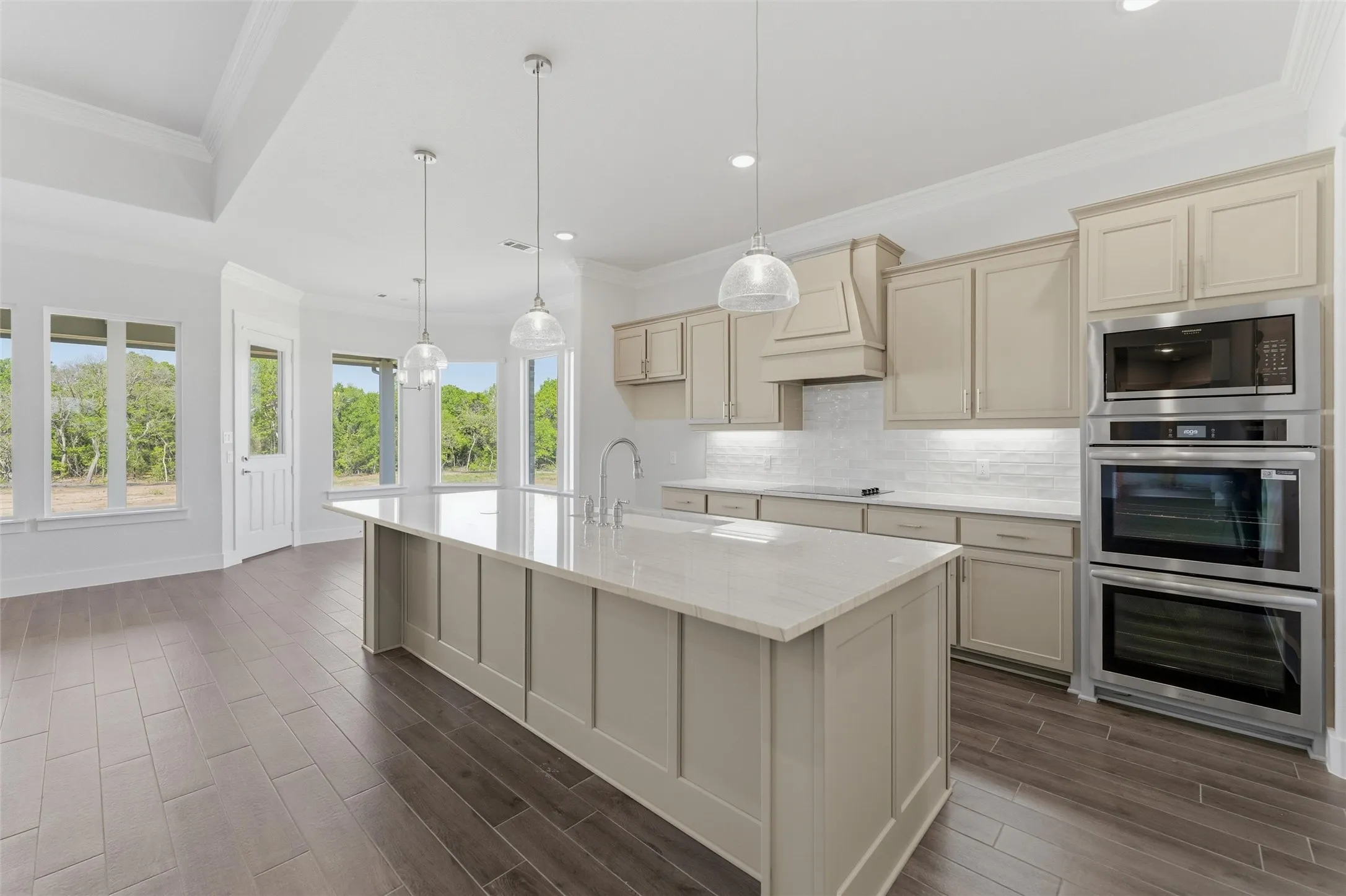 Kitchen featuring cream cabinetry, stainless steel appliances, a large island, light stone countertops, and ornamental molding