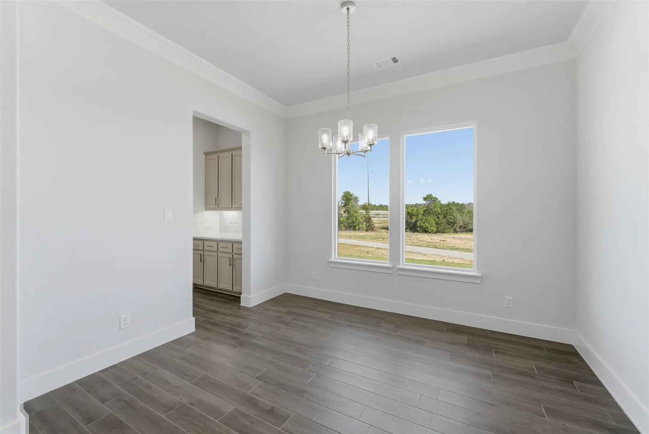 Unfurnished dining area with a chandelier, dark wood-type flooring, and ornamental molding