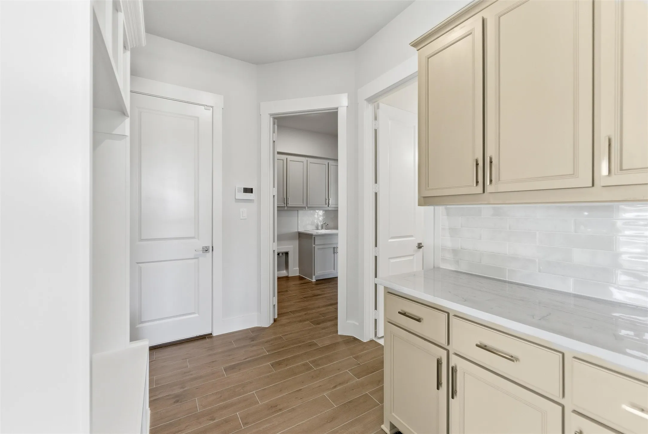 Kitchen with wood tiled floors, backsplash, and cream cabinets