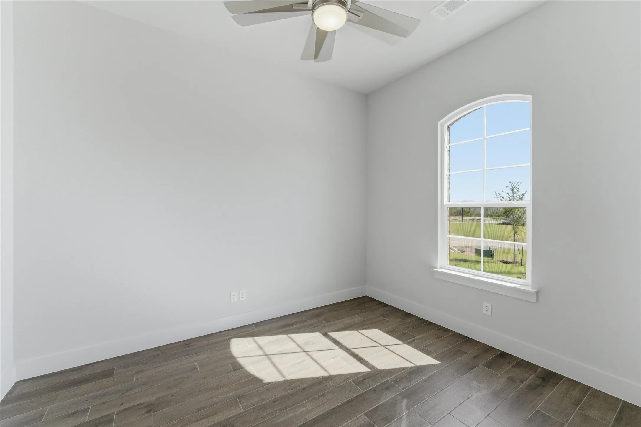 Empty room with dark wood-style floors and ceiling fan