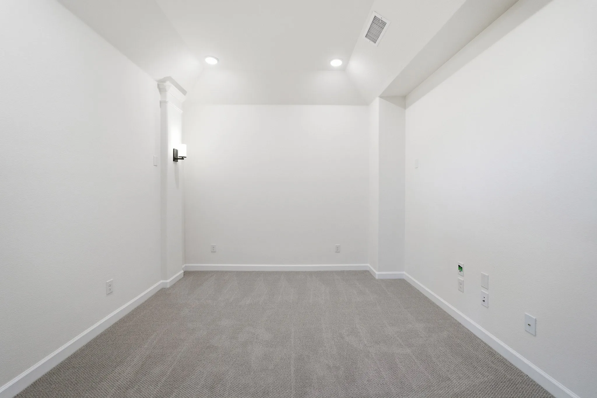 Carpeted room featuring recessed ceiling lighting and a wall sconce