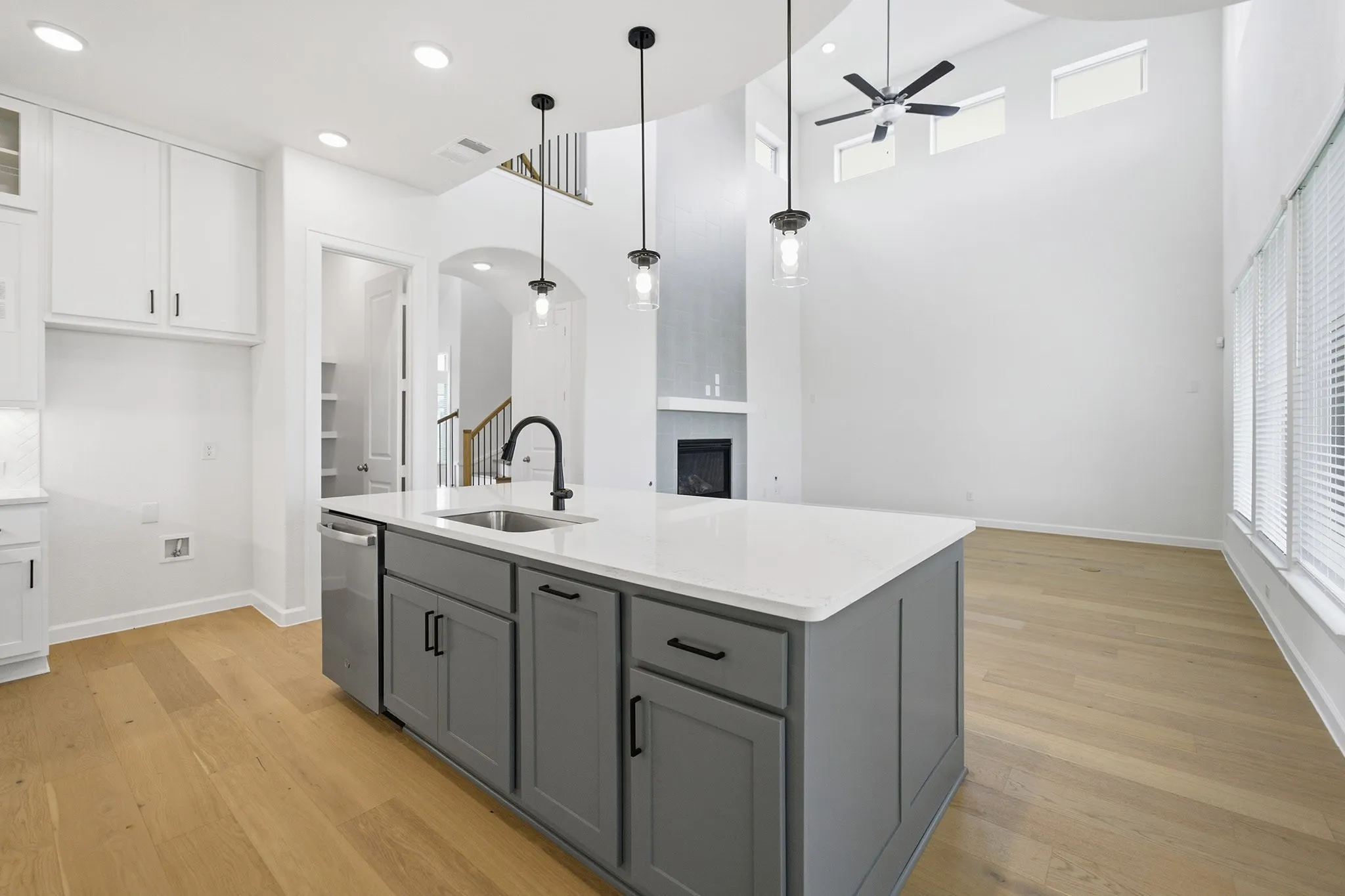 Kitchen island with a light-toned countertop, gray cabinetry, and an undermount sink with a matte black faucet