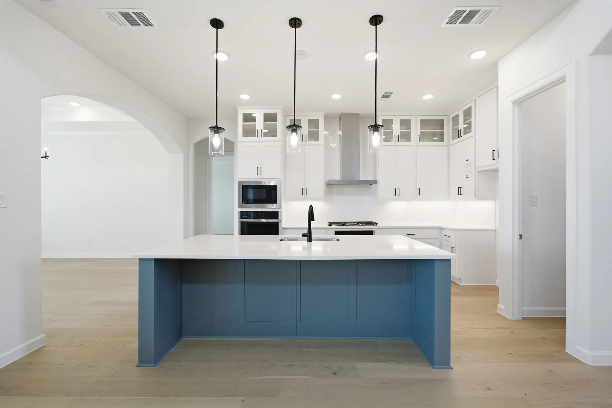Modern kitchen featuring a blue-paneled island with a white countertop and three pendant lights