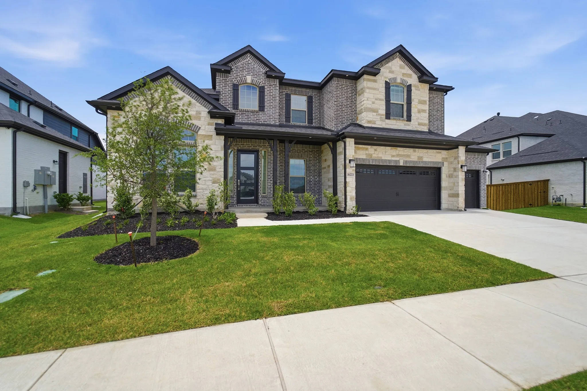 Two-story residence featuring a combination brick and stone facade with dark trim accents