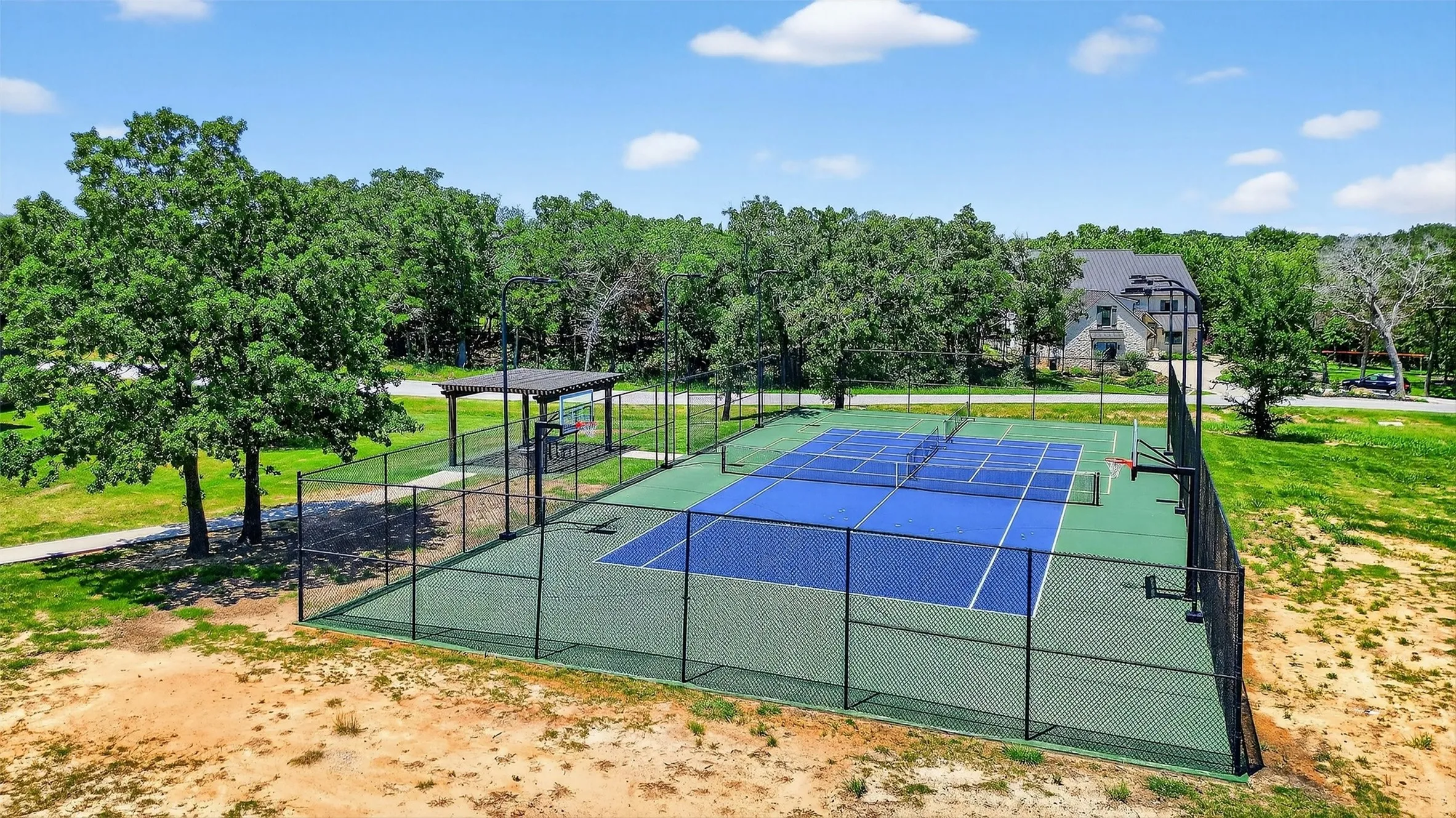 View of tennis court featuring view of wooded area