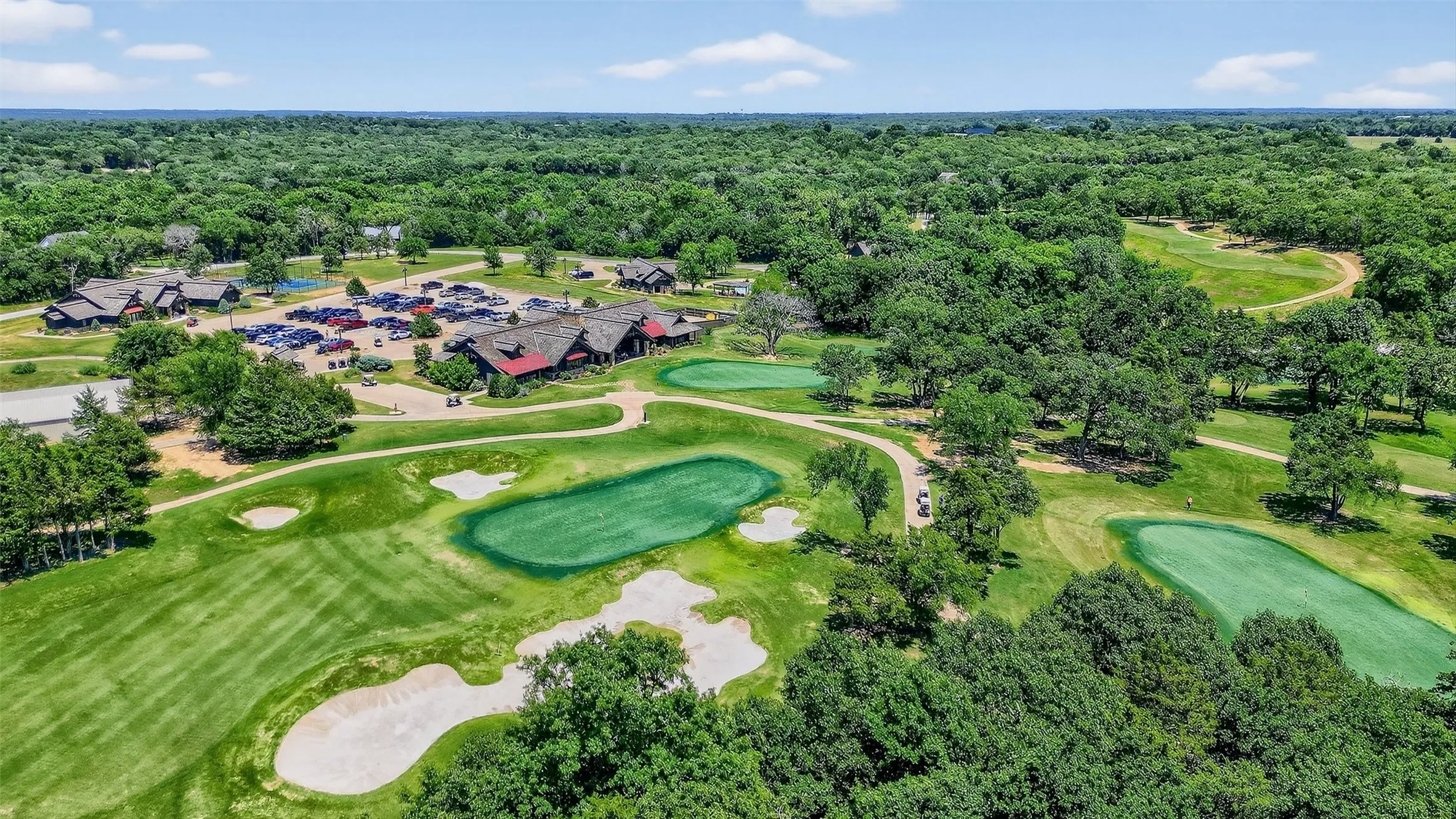 Aerial view of property and surrounding area with a golf course and a forest