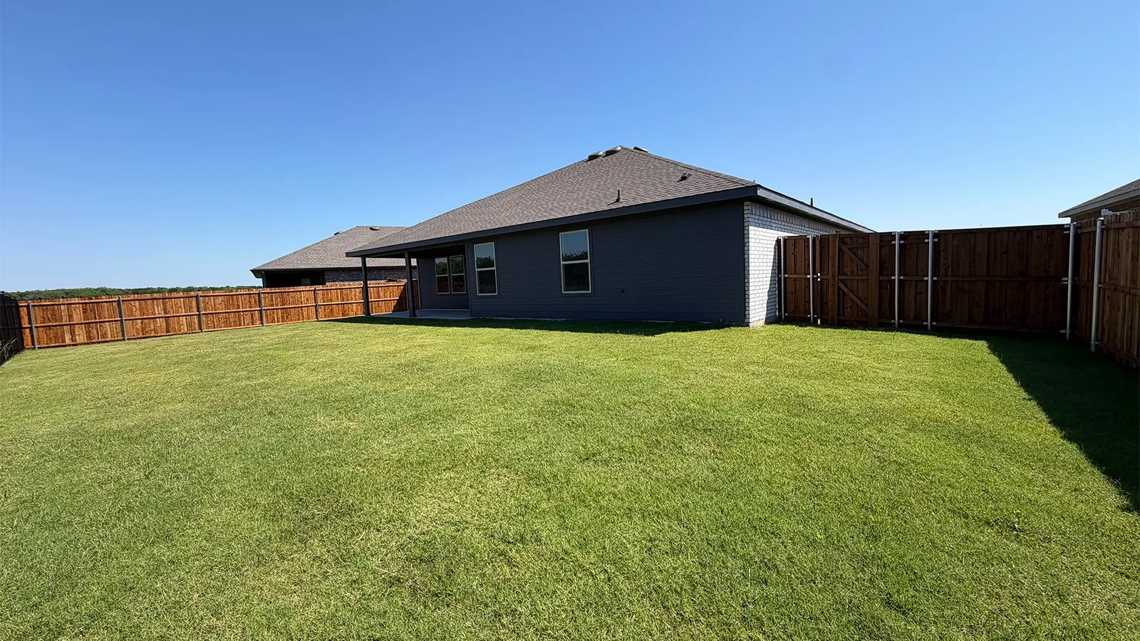 Expansive grassy backyard featuring a full privacy fence
