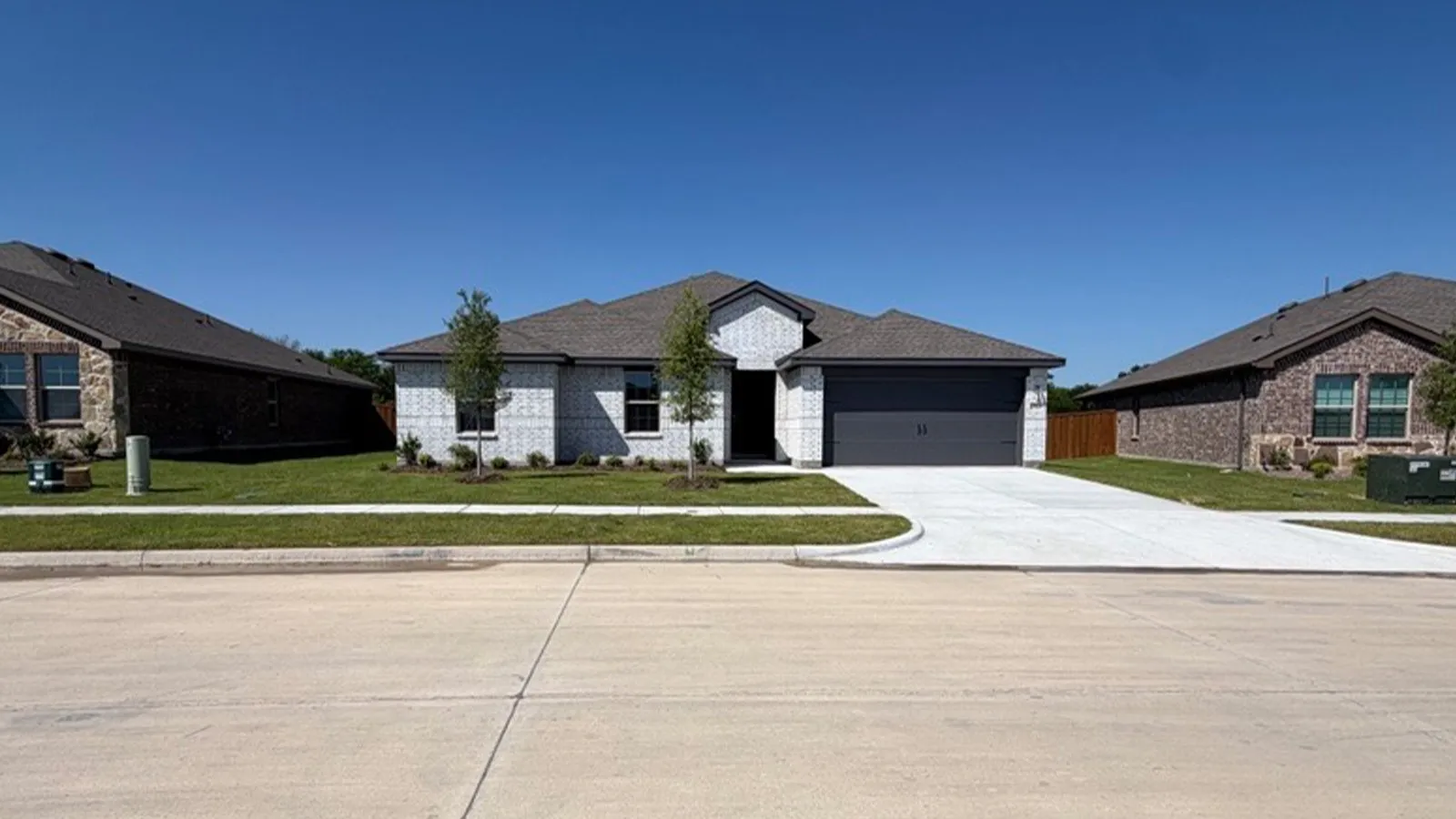 Single-story residence featuring a light-colored brick exterior facade, a dark gray garage door, and a matching dark gray shingle roof
