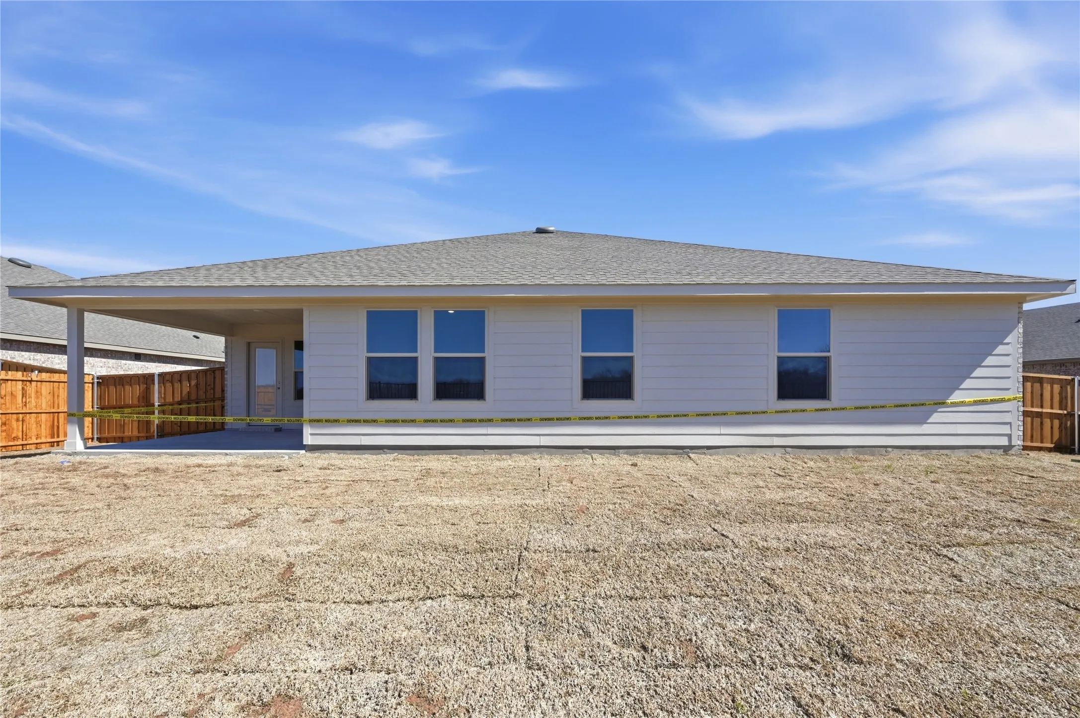 Rear exterior featuring a covered patio, neutral siding, multiple windows, a shingled roof, and a privacy fence