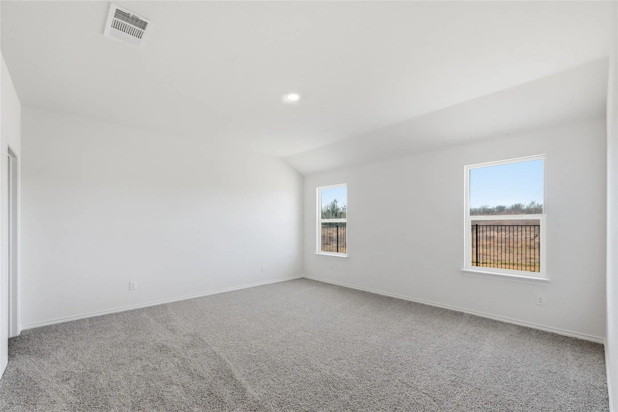 Spacious interior room featuring light gray carpeting and white painted walls