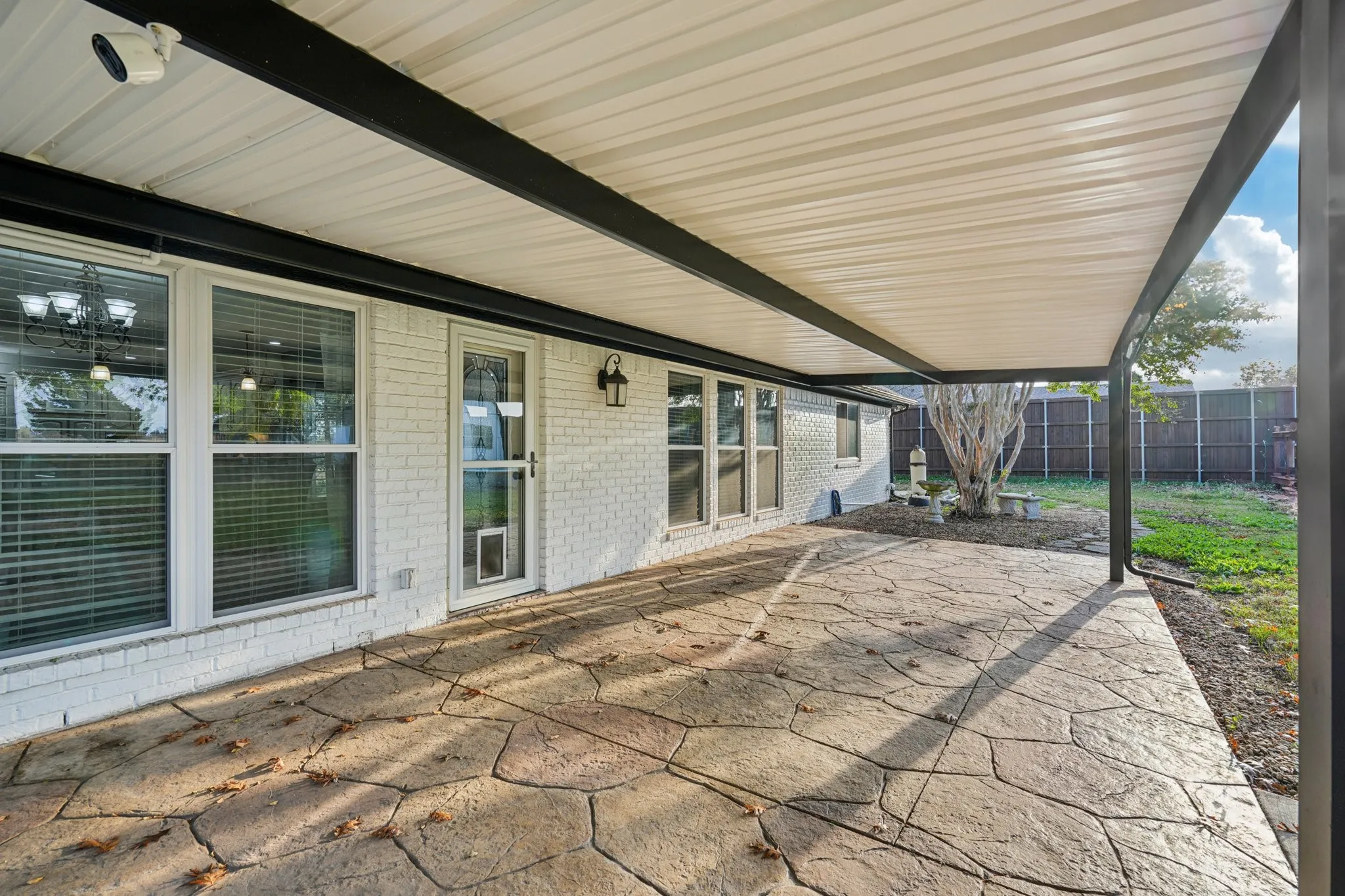 Fenced backyard with a large covered patio area