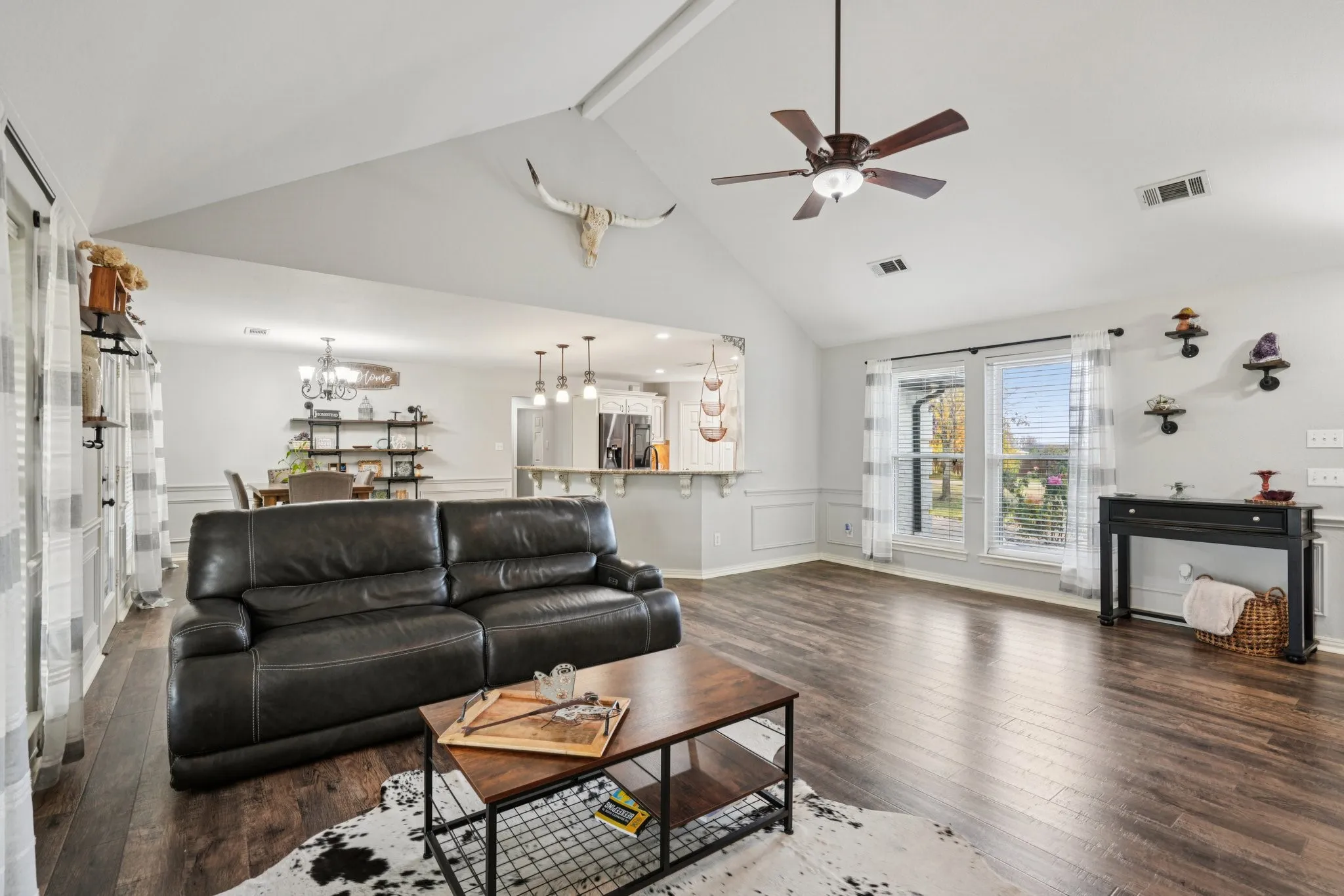 Living room with high vaulted and beamed ceiling, a chandelier, and ceiling fan
