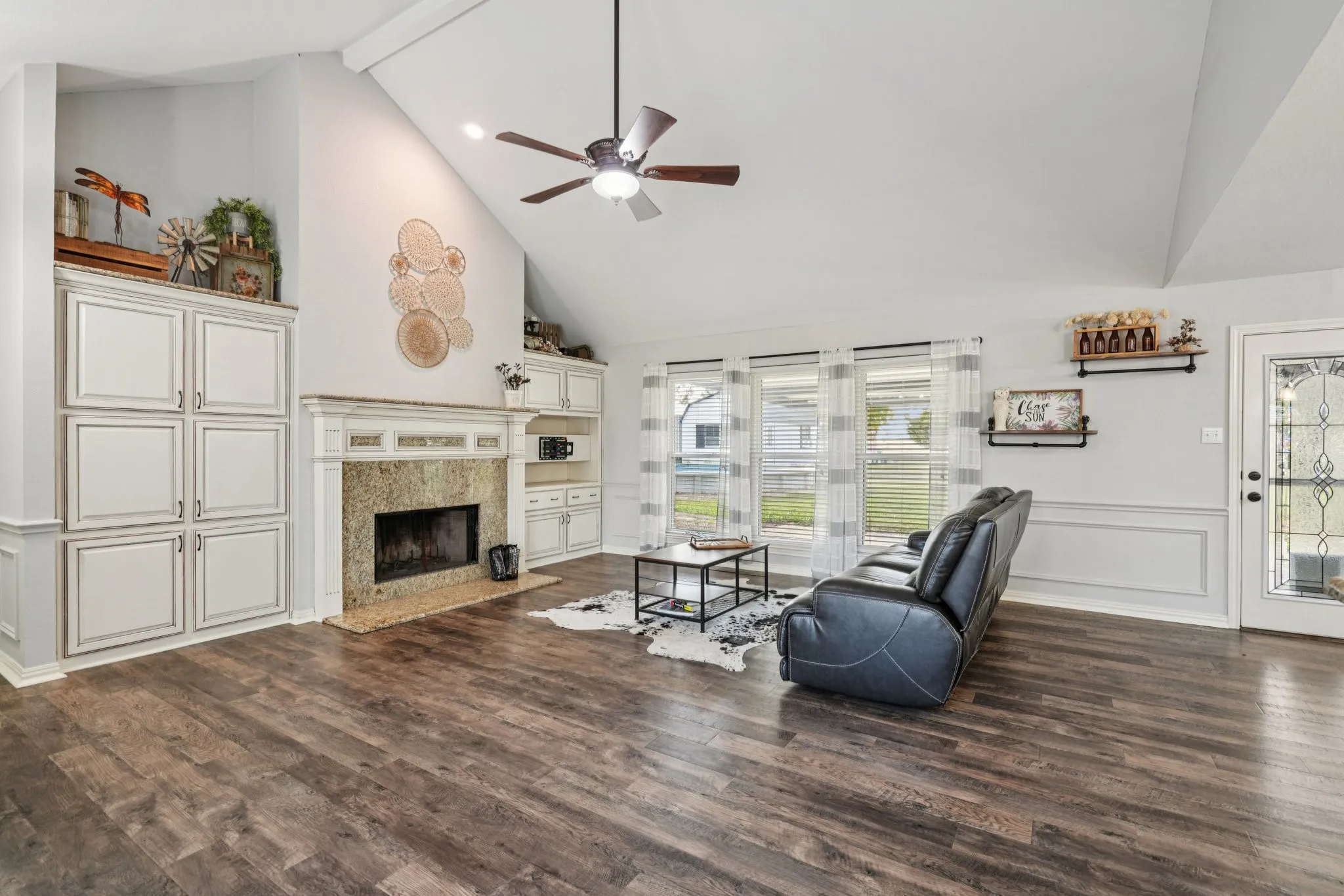 Living room with high vaulted ceiling, LVP Flooring, Fireplace and custom cabinets