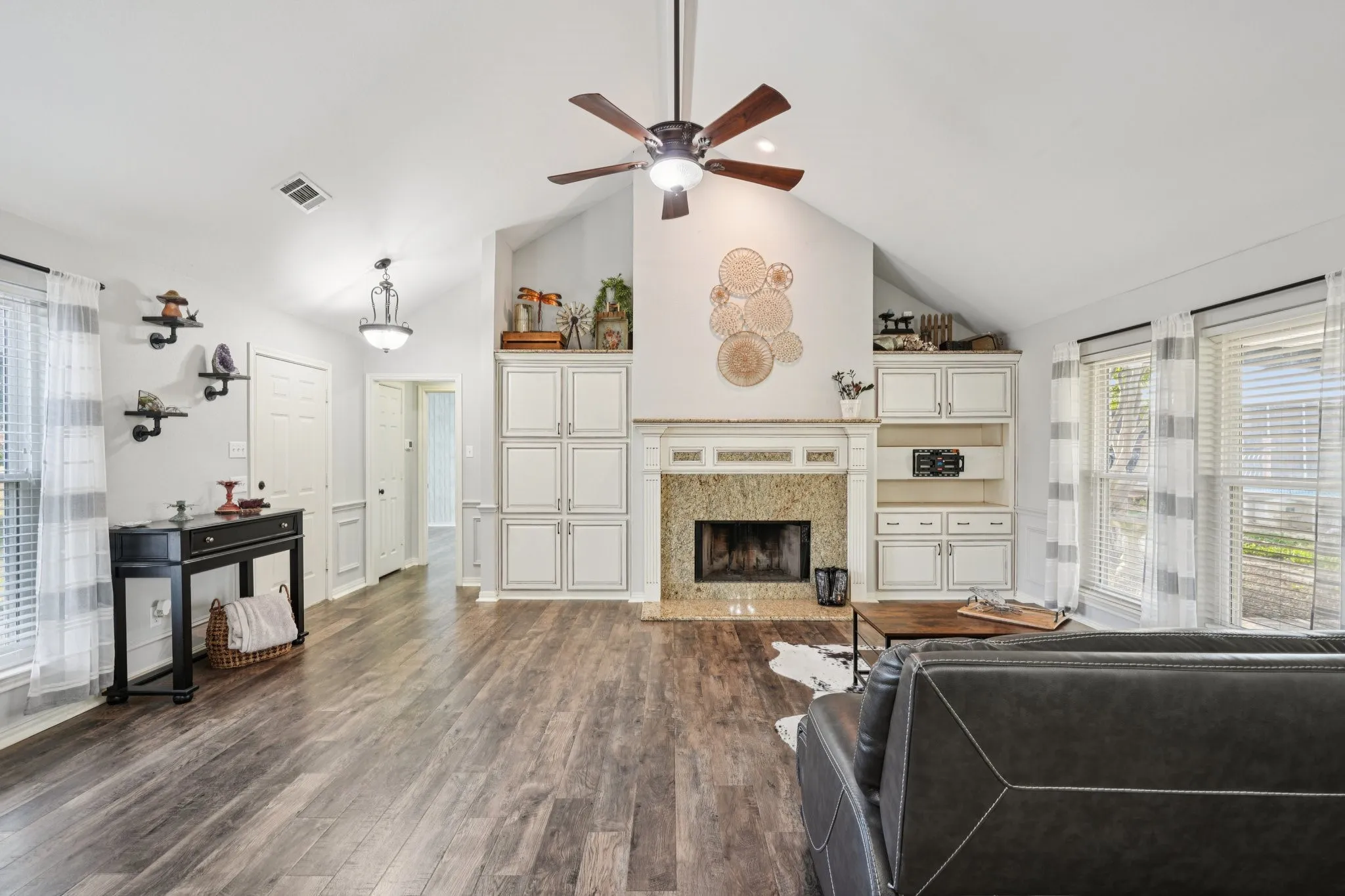 Living room with a high end fireplace, high vaulted ceiling, custom cabinets, LVP flooring