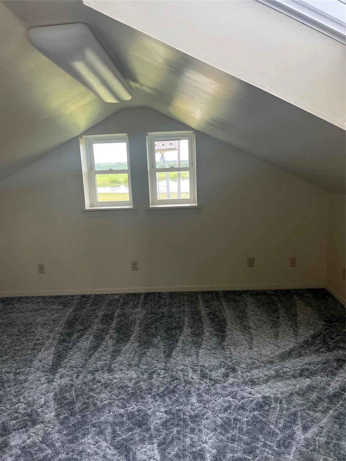 Bonus room with lofted ceiling and dark carpet