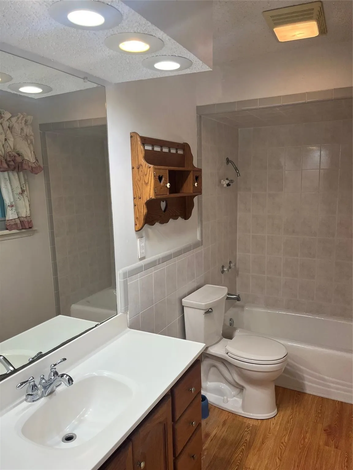 Full bathroom featuring light wood finished floors, vanity, bathtub / shower combination, a textured ceiling, and tile walls