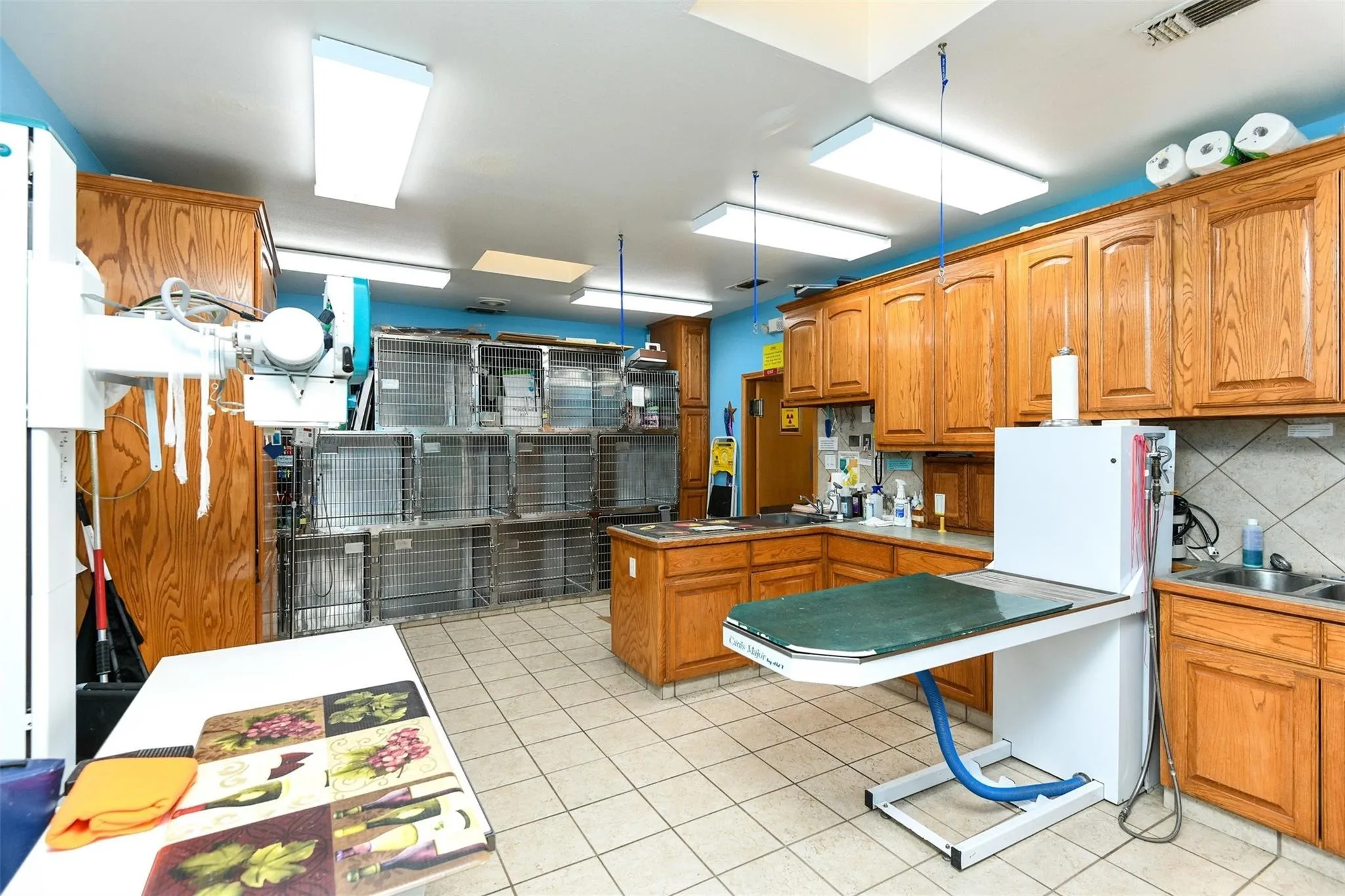 Kitchen featuring decorative backsplash, brown cabinets, light tile patterned flooring, and freestanding refrigerator