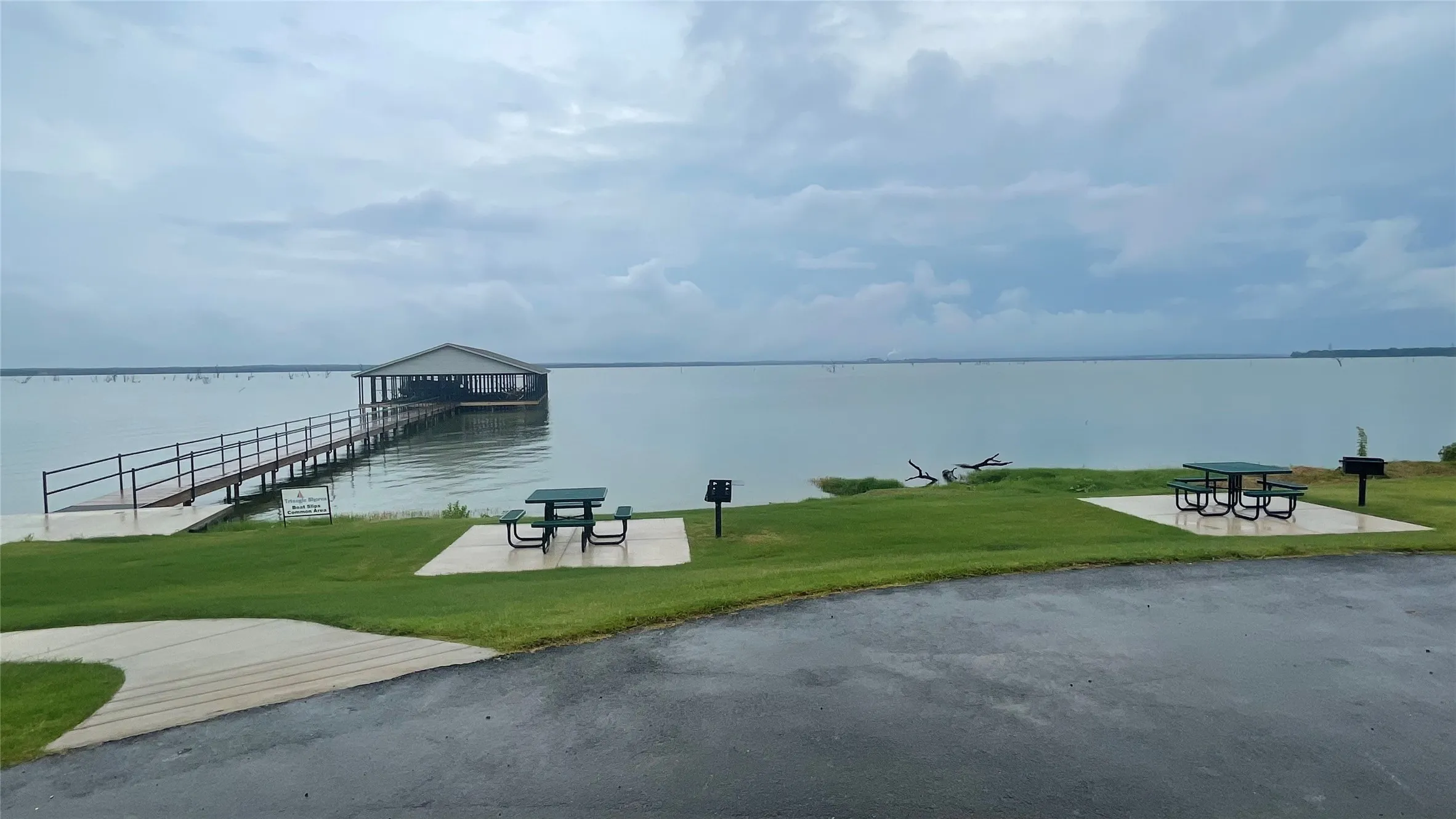 View of dock with a patio, a water view, and a yard
