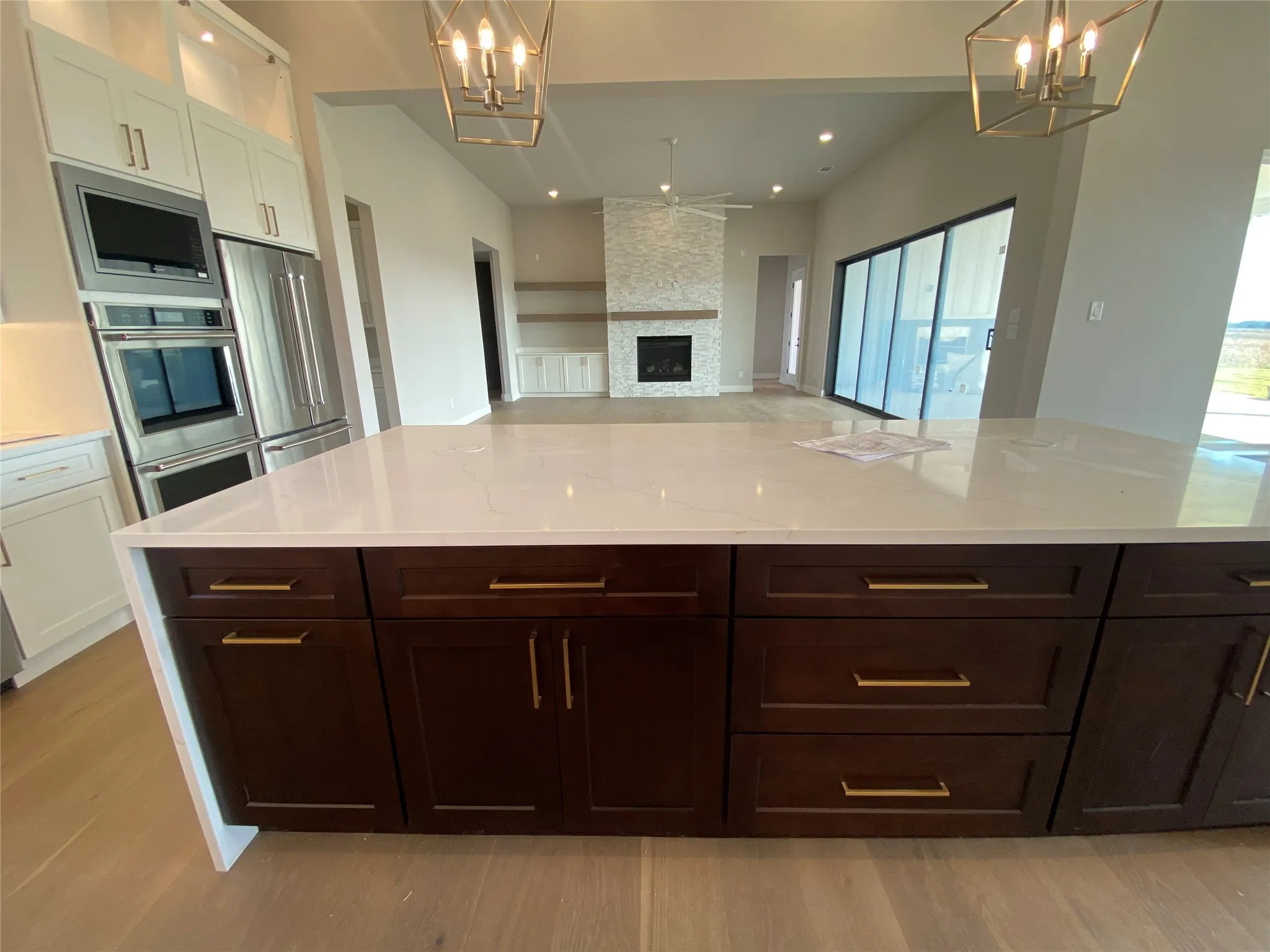 Kitchen with a chandelier, hanging light fixtures, open floor plan, stainless steel appliances, and dark brown cabinets