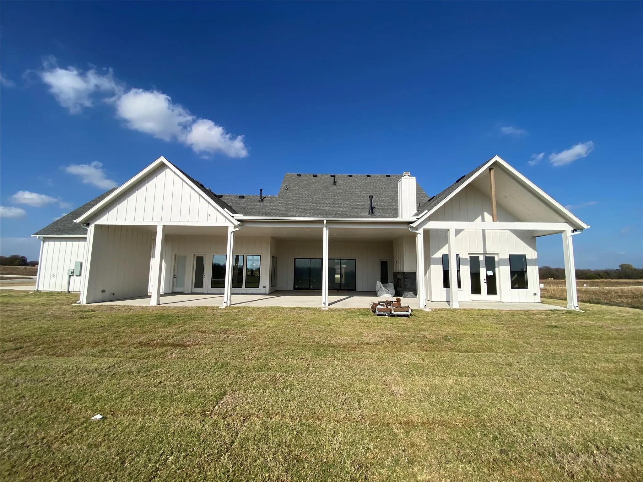 Back of house with a patio, a yard, a chimney, board and batten siding, and french doors