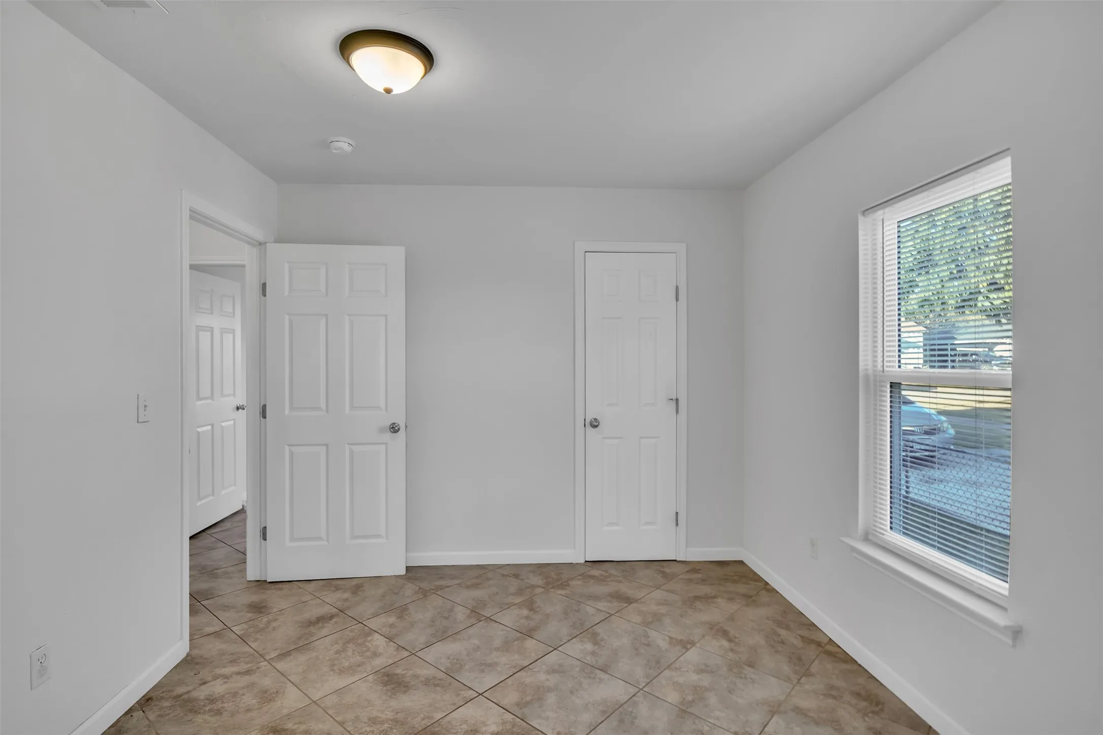 Unfurnished bedroom featuring light tile patterned floors and baseboards