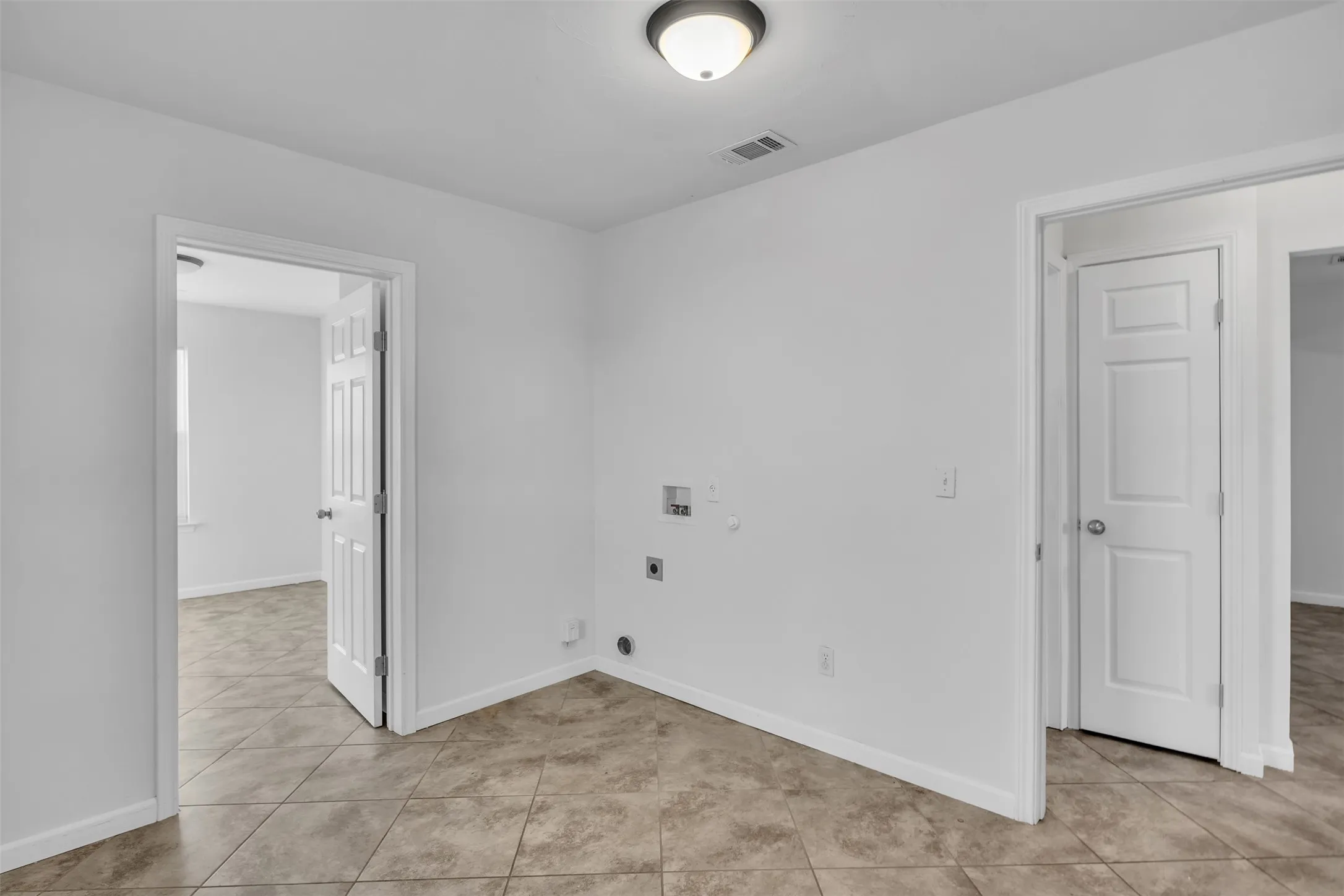 Laundry area with hookup for a gas dryer, light tile patterned flooring, hookup for a washing machine, and hookup for an electric dryer