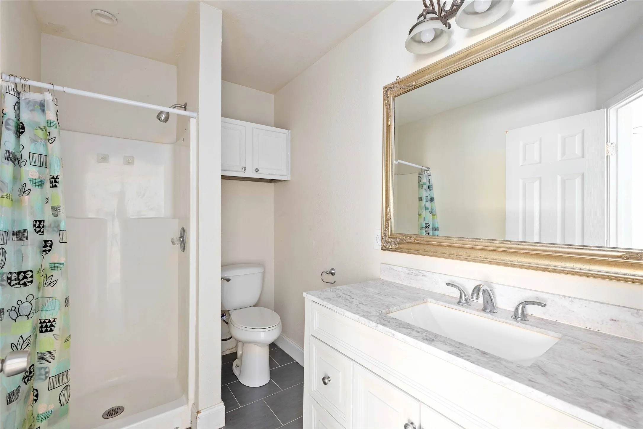 Primary bathroom with a shower stall, vanity, and dark tile patterned floors