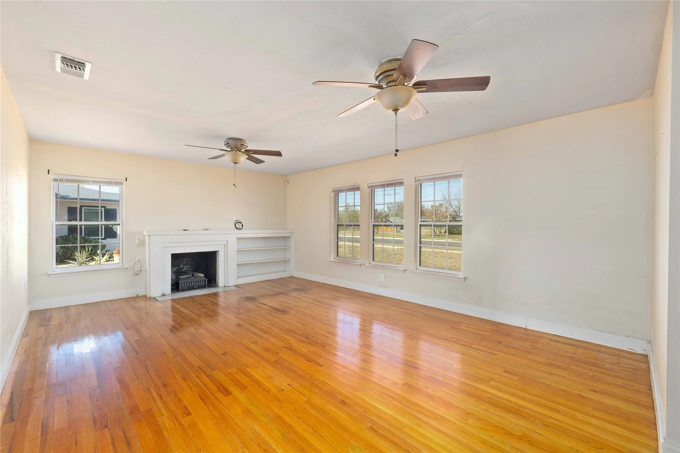 Unfurnished living room with light wood-type flooring, a fireplace with flush hearth, and ceiling fan