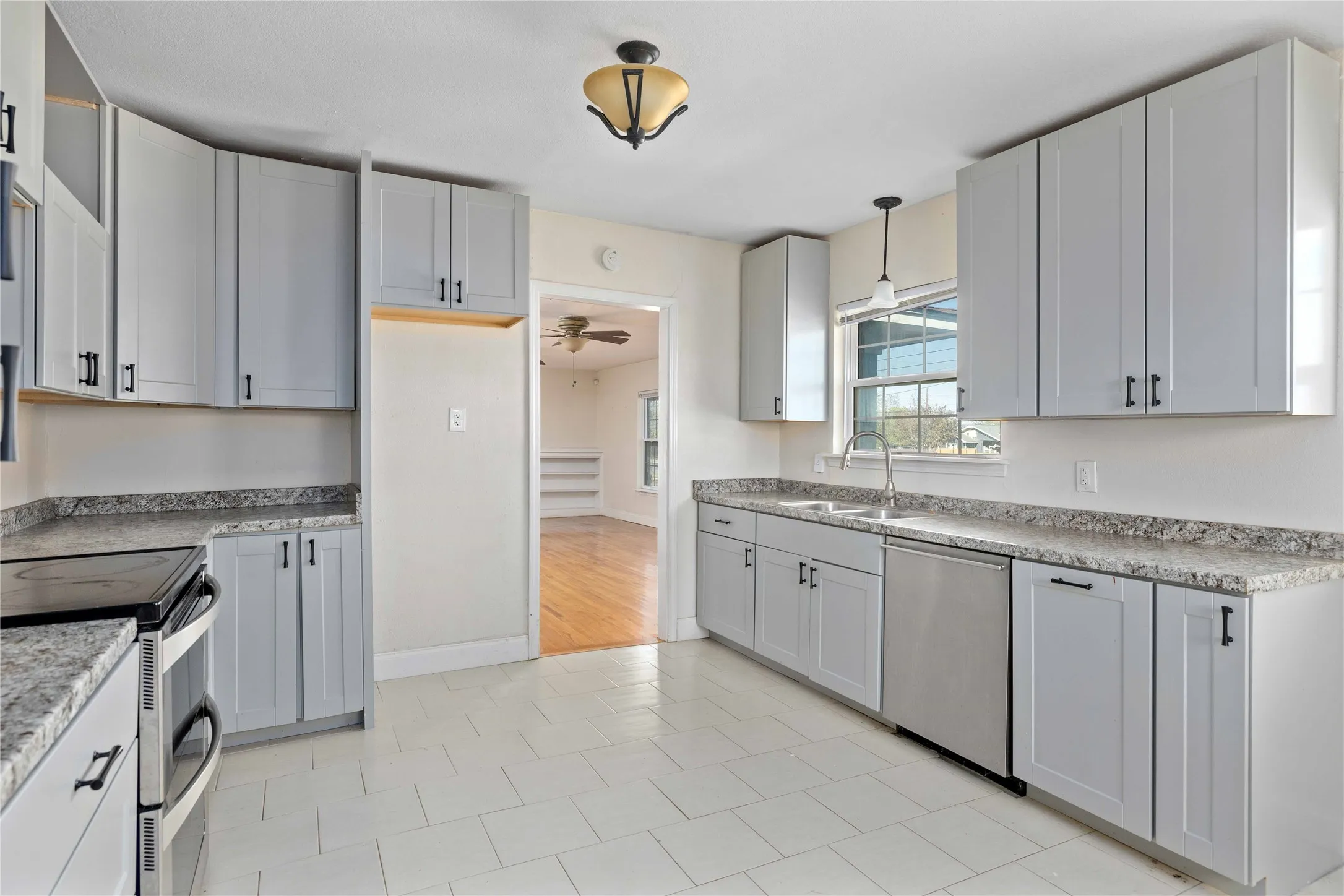 Kitchen with stainless steel appliances, decorative light fixtures, a ceiling fan, and light tile patterned floors
