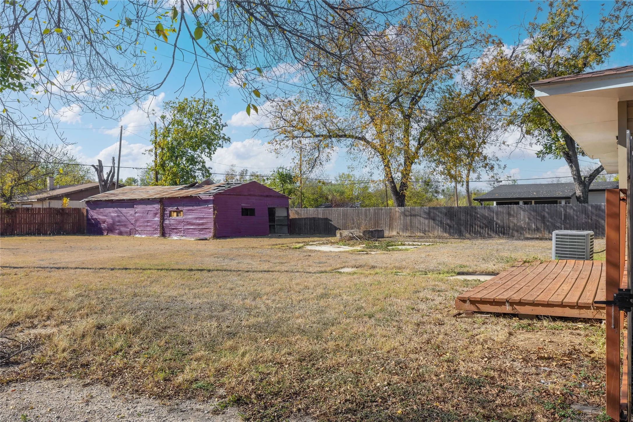 Fenced backyard featuring a wooden deck and an outdoor structure
